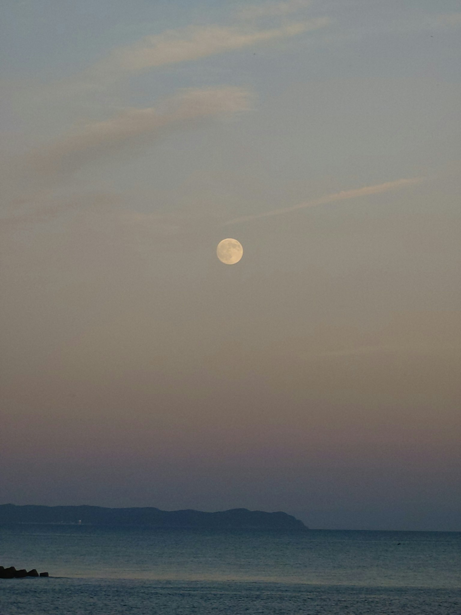 Luna llena sobre el mar tranquilo con cielo pastel