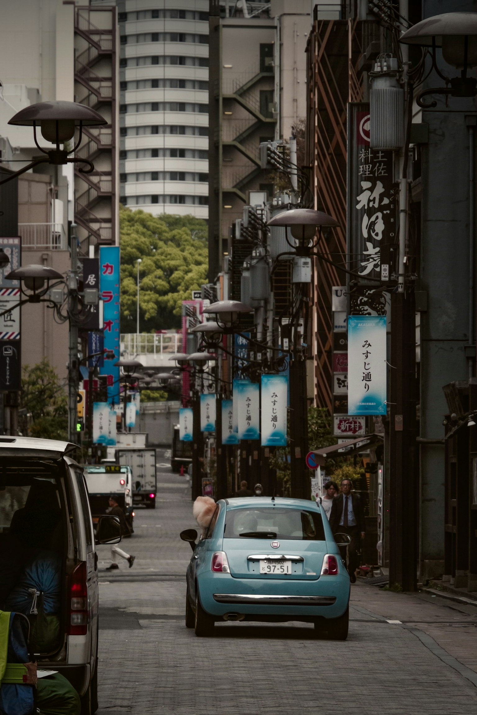 一条狭窄的街道，停着一辆蓝色的车，两侧有各种标志