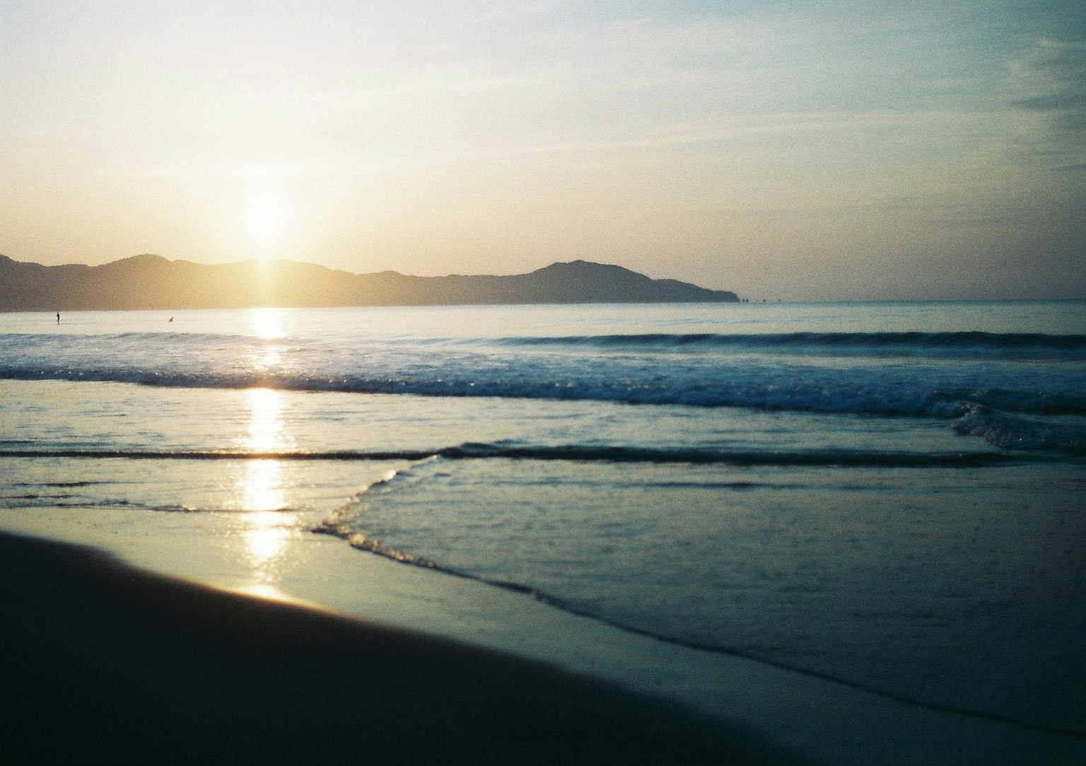 Pemandangan pantai tenang dengan matahari terbenam dan ombak lembut