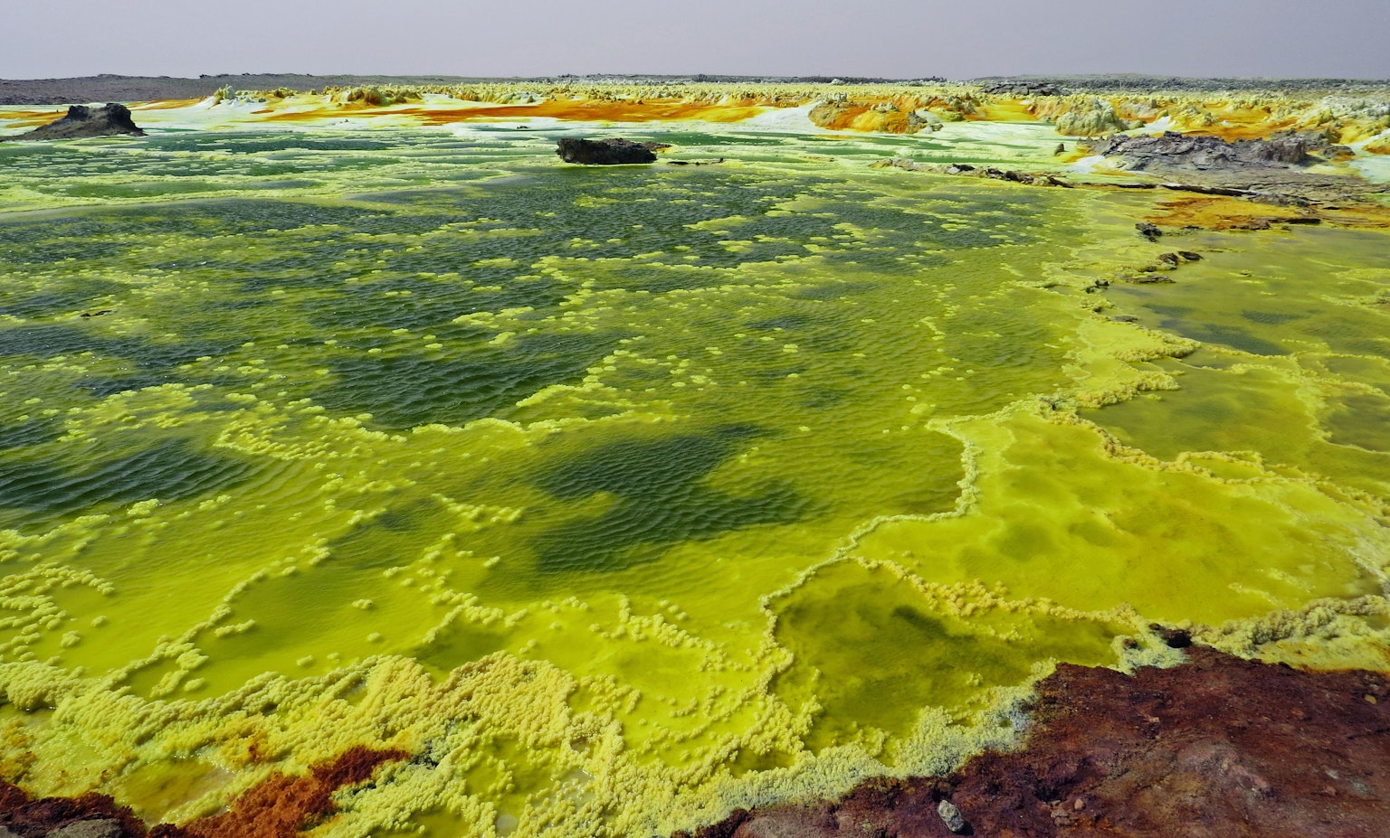 Green sulfur lake with surrounding landscape