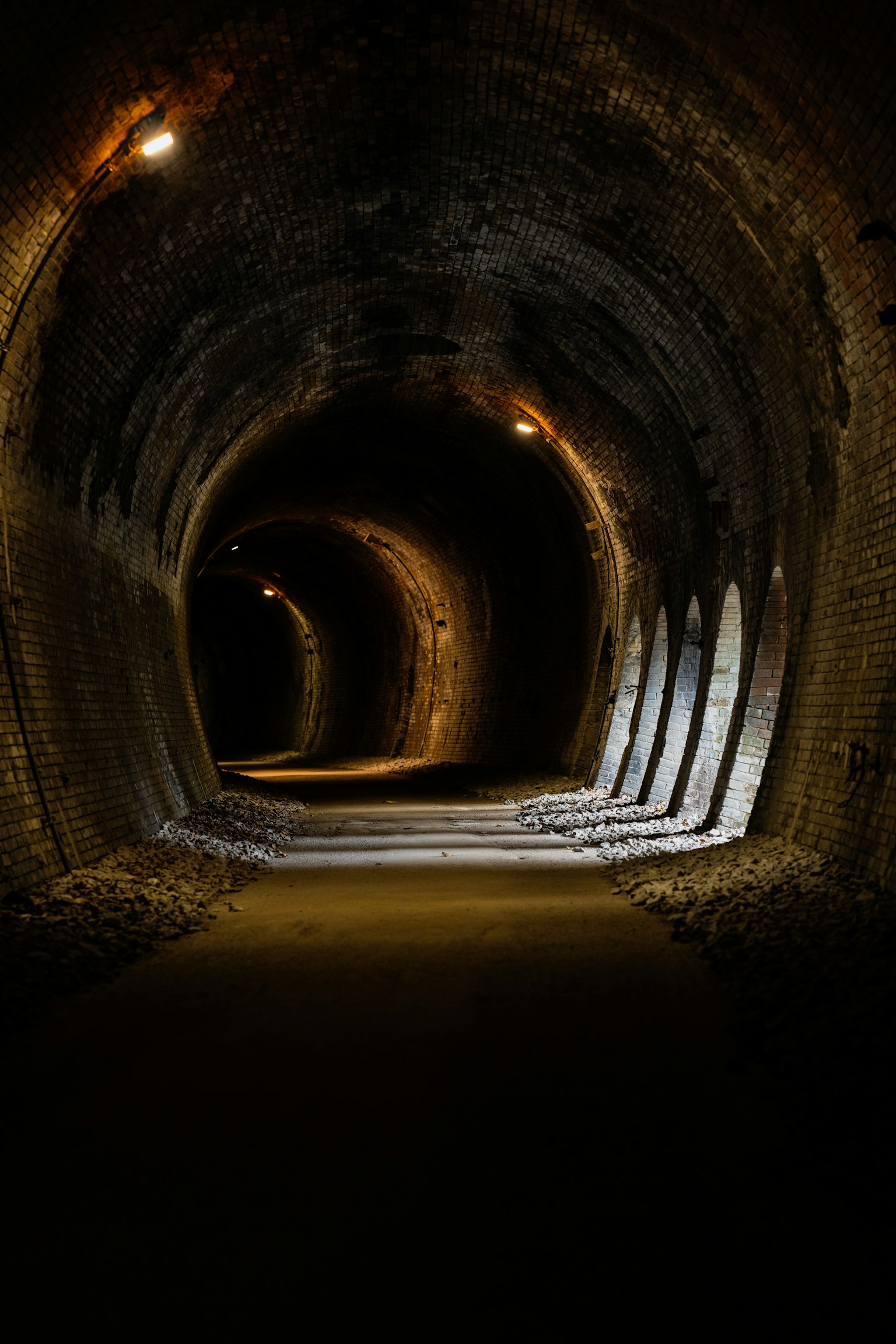 暗いトンネルの内部が見える写真で、照明がトンネルの曲がりを照らしている
