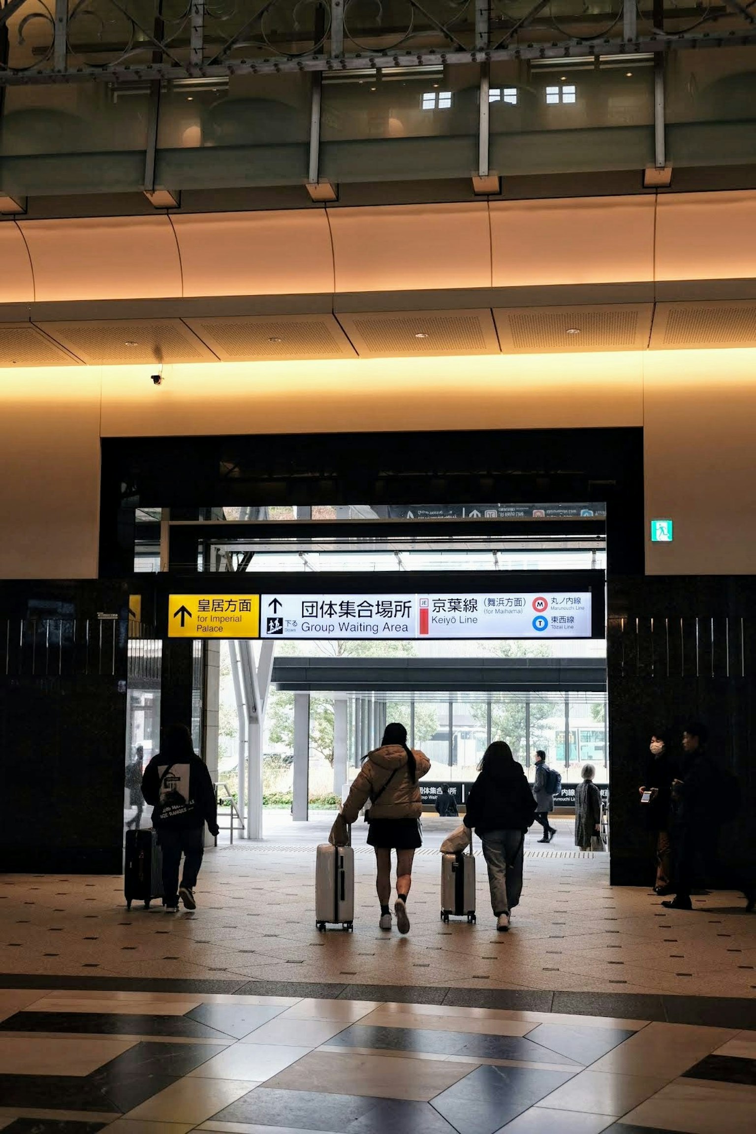 Viaggiatori con valigie che camminano attraverso l'ingresso di una stazione moderna