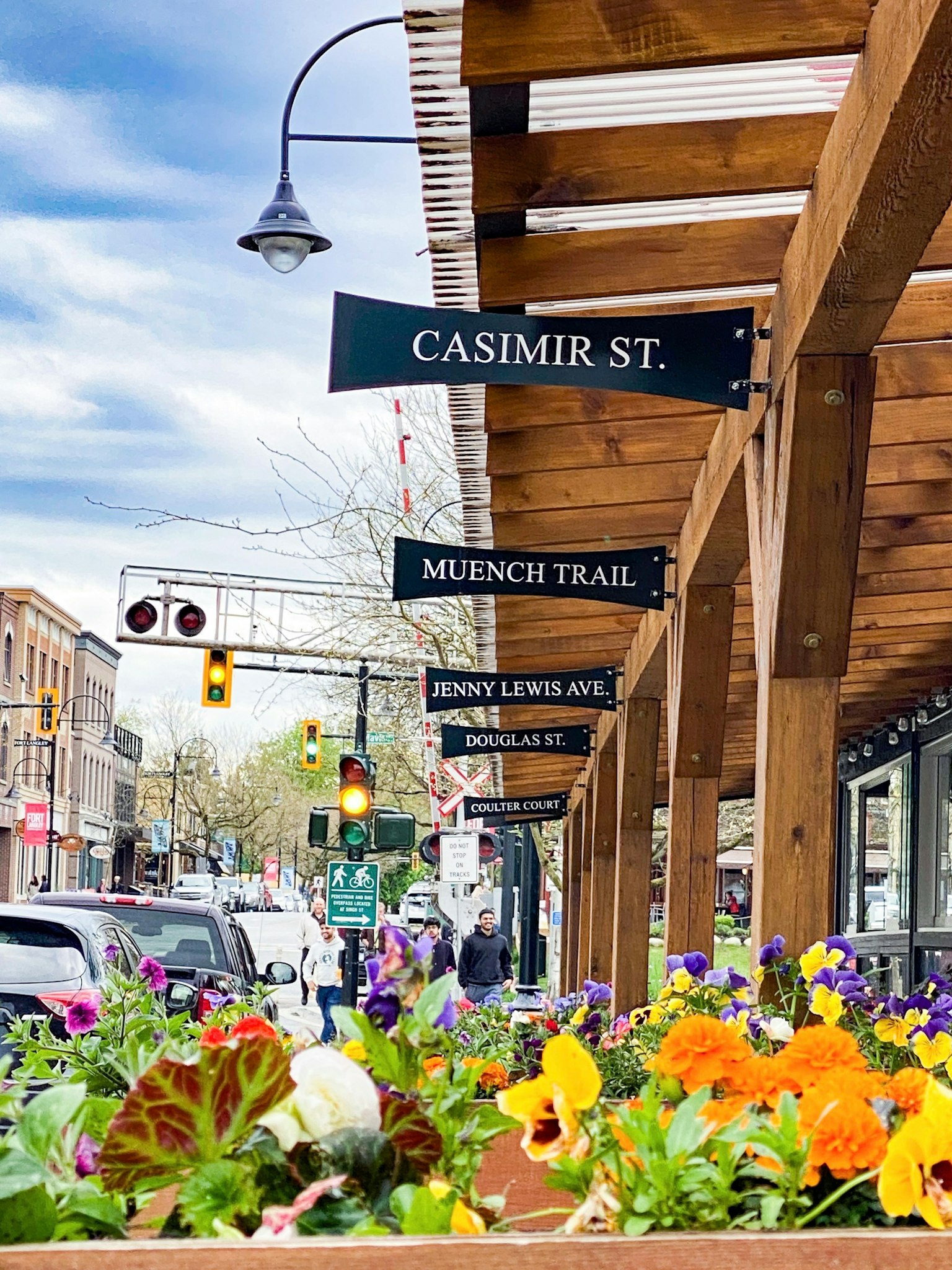 Vue de la rue avec le panneau de la rue Casimir et des fleurs colorées en pleine floraison