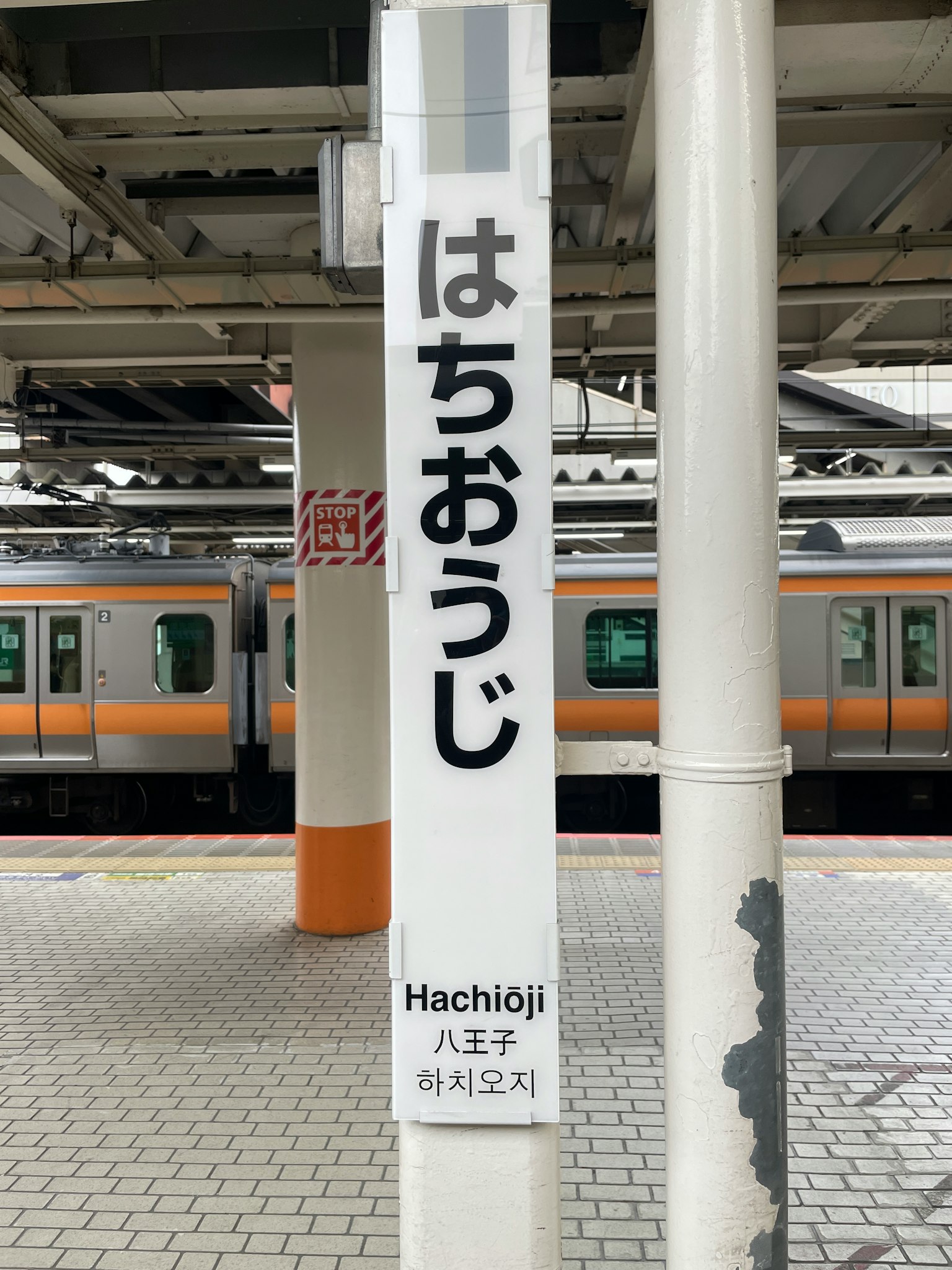 八王子站的标志，背景中可见火车