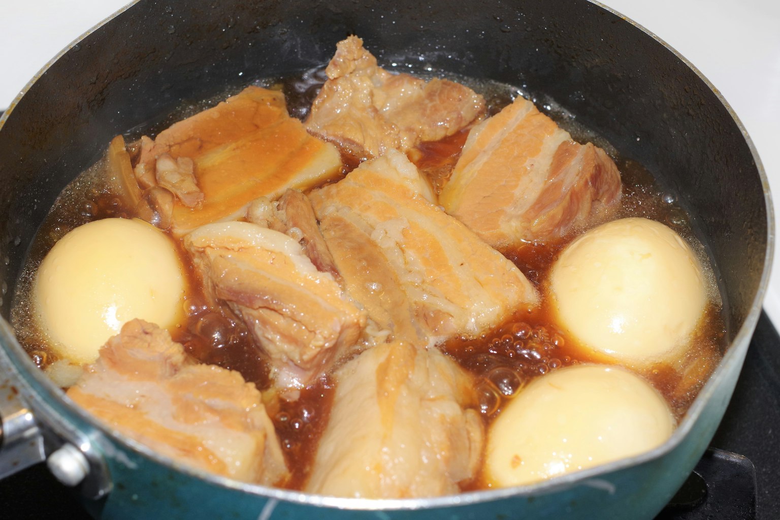 Une casserole contenant de la viande bouillie et des œufs dans un bouillon savoureux