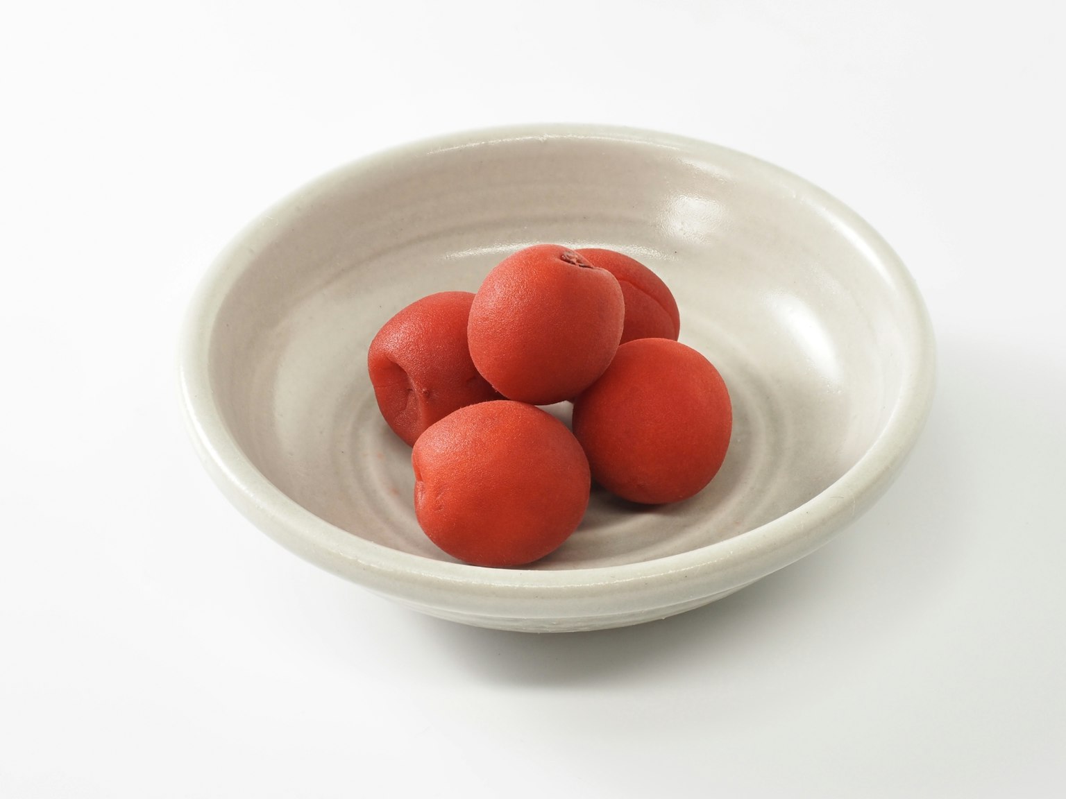 Six boules rouges disposées dans un plat blanc