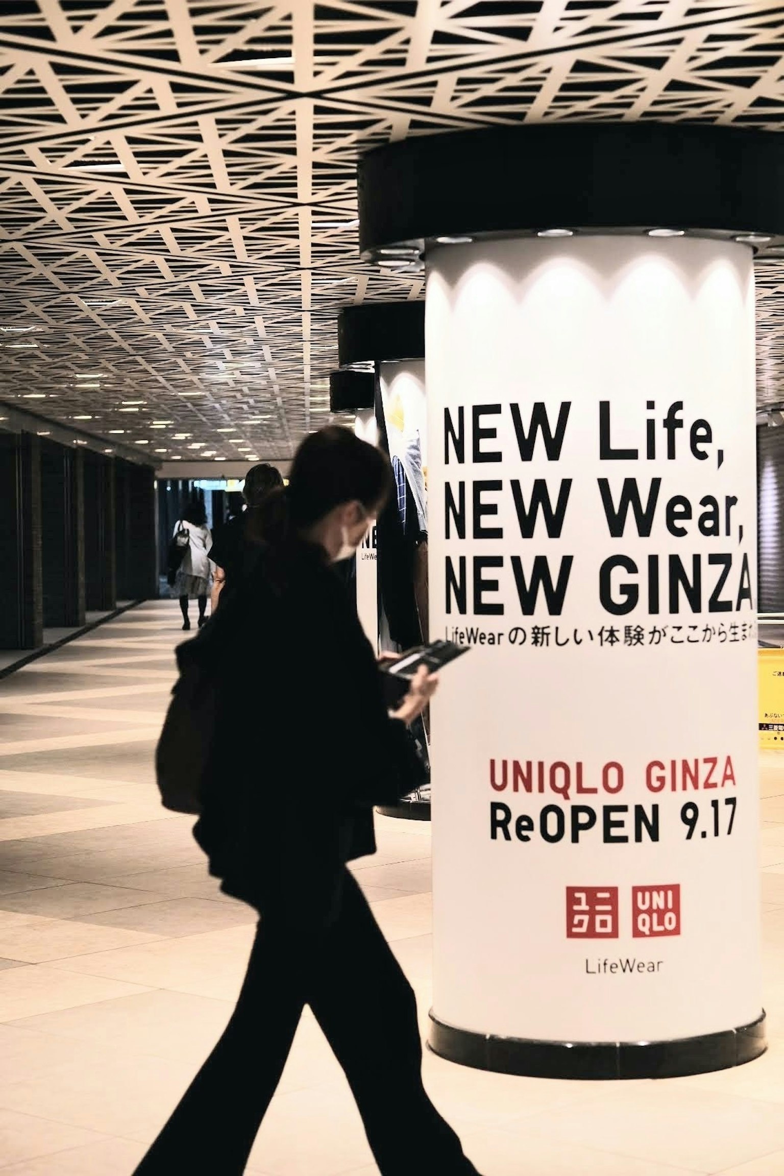 Personne marchant devant une publicité UNIQLO à Ginza promouvant une nouvelle vie et des vêtements
