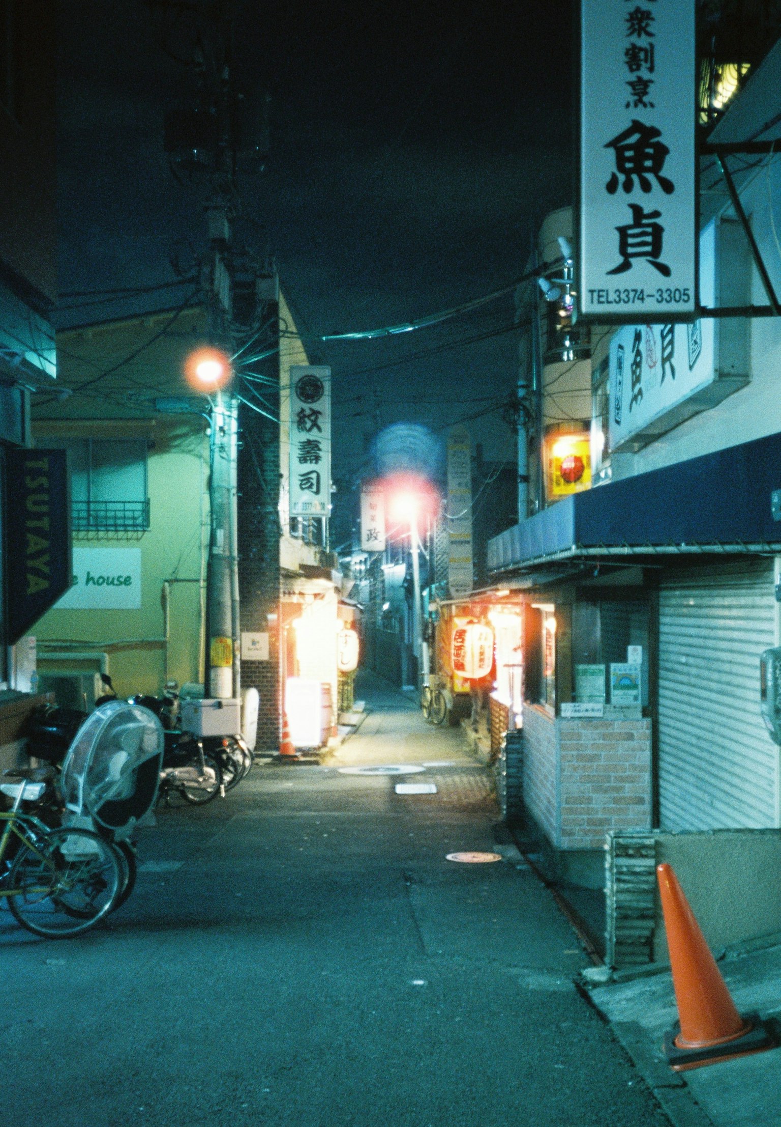 Callejón estrecho iluminado por letreros de neón por la noche