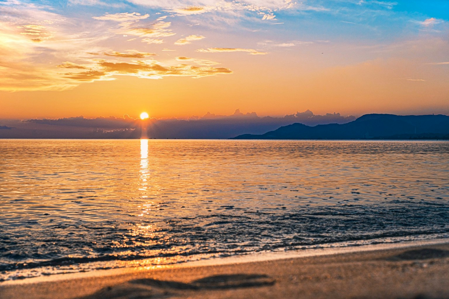 Magnifique paysage marin avec le coucher de soleil se reflétant sur l'eau et des vagues douces