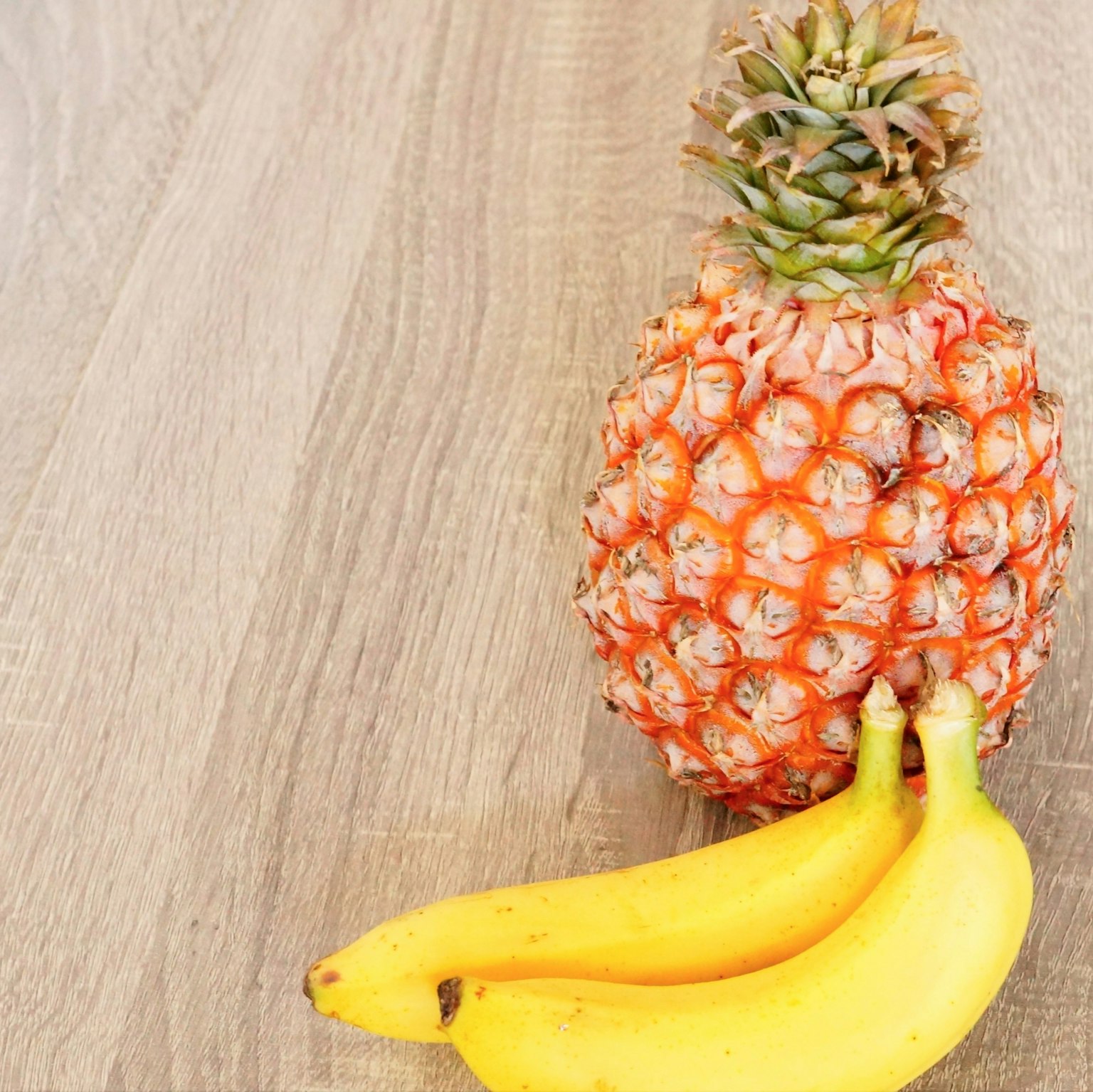 Ananas e banane su un tavolo di legno
