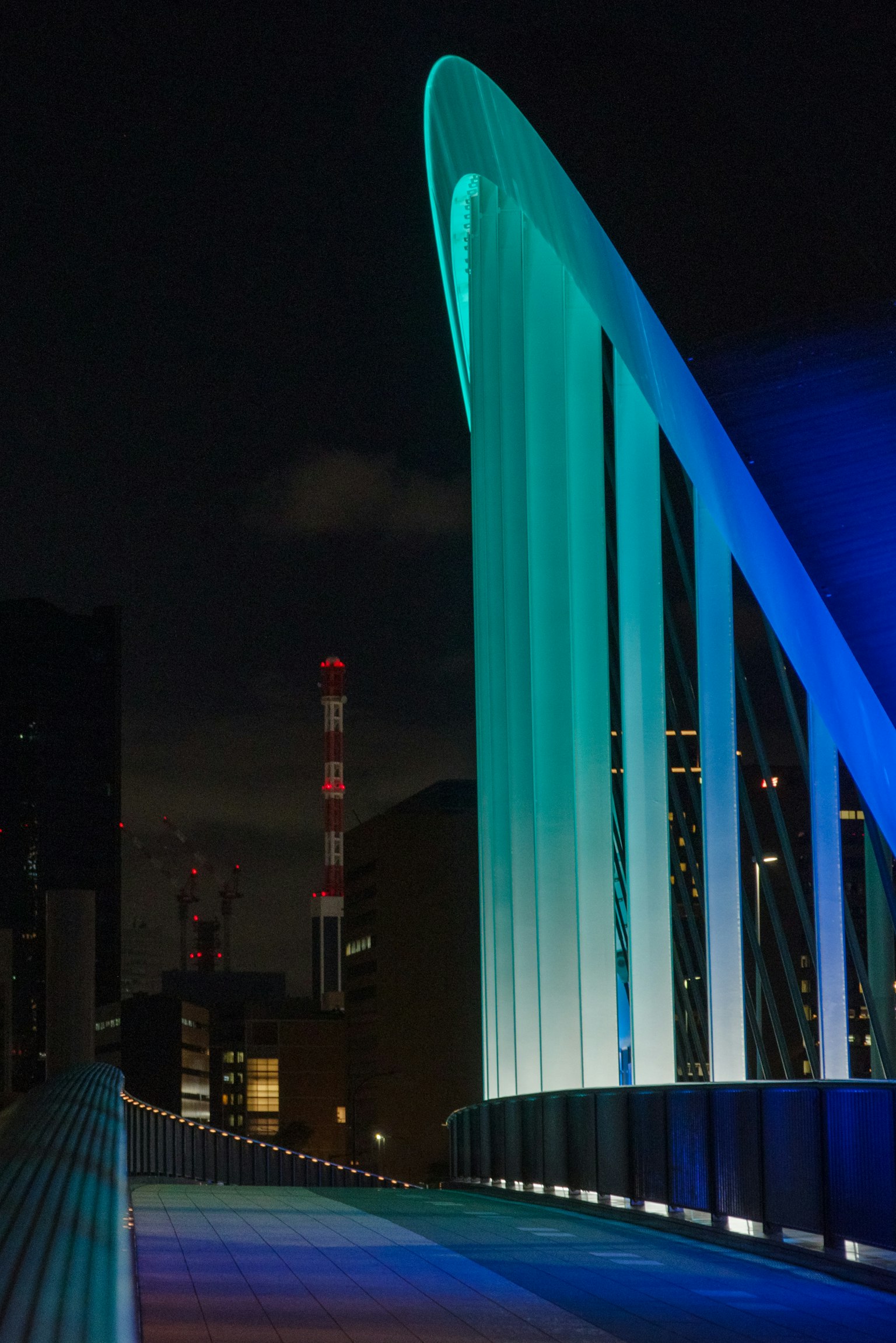 Design moderno del ponte illuminato di blu contro un paesaggio urbano notturno