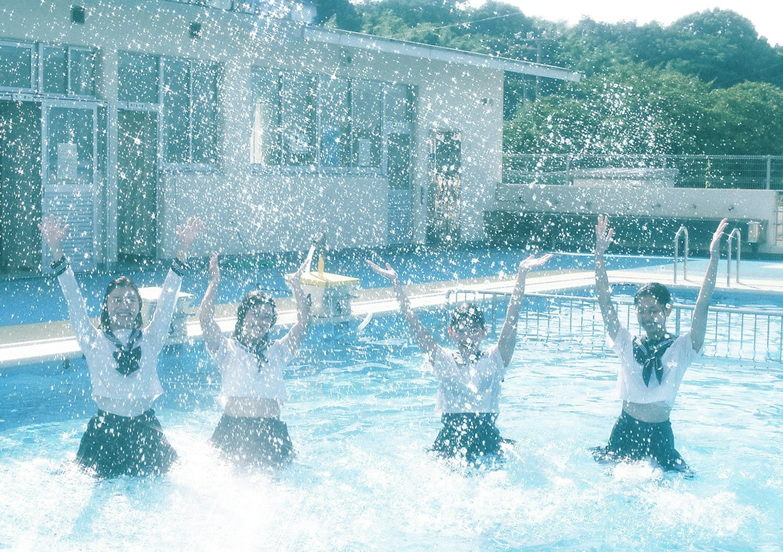 Four girls splashing water in a pool