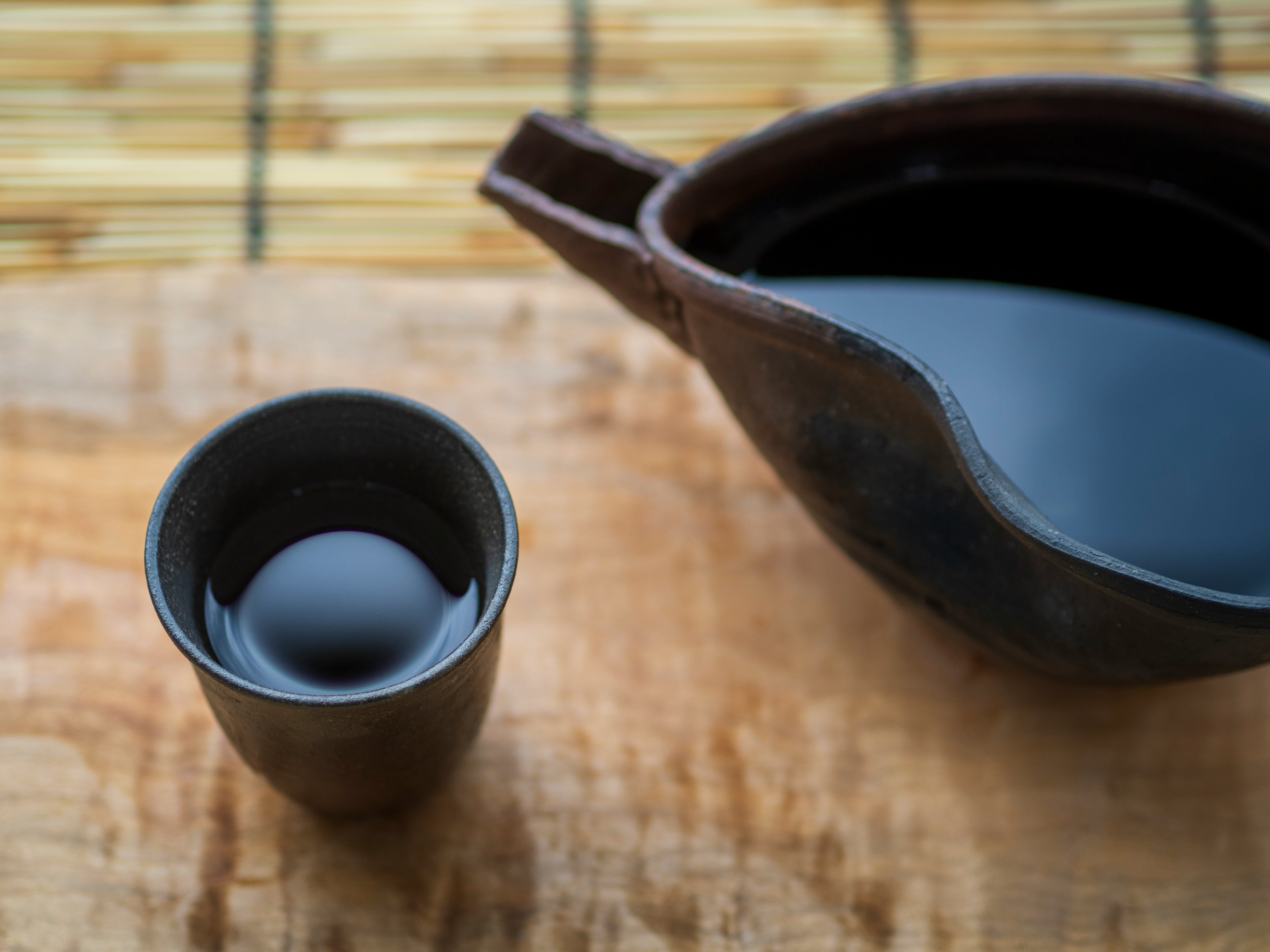 竹の敷物の上にある茶器と湯のみ