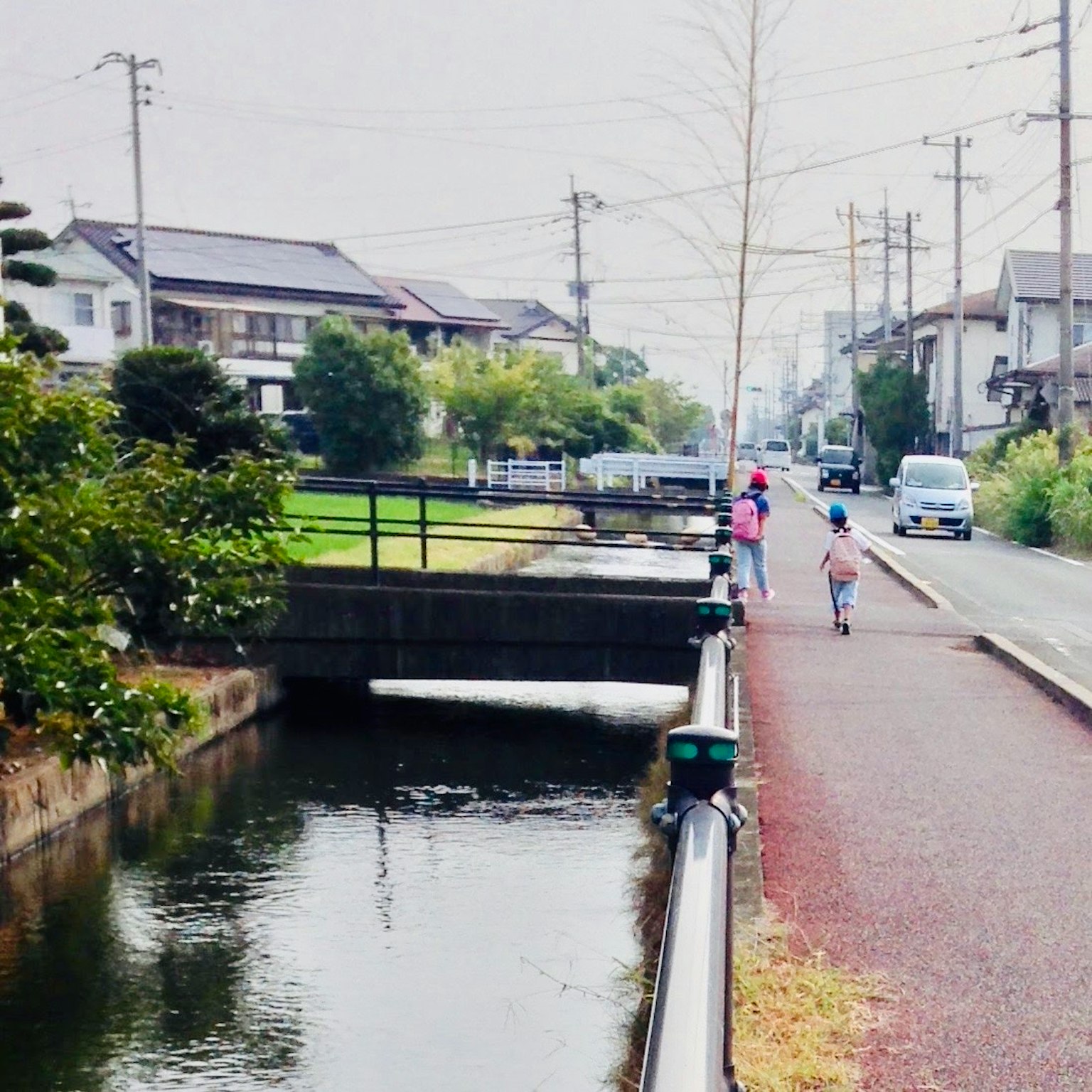 Scena di bambini che camminano lungo un sentiero tranquillo lungo il fiume con case sullo sfondo