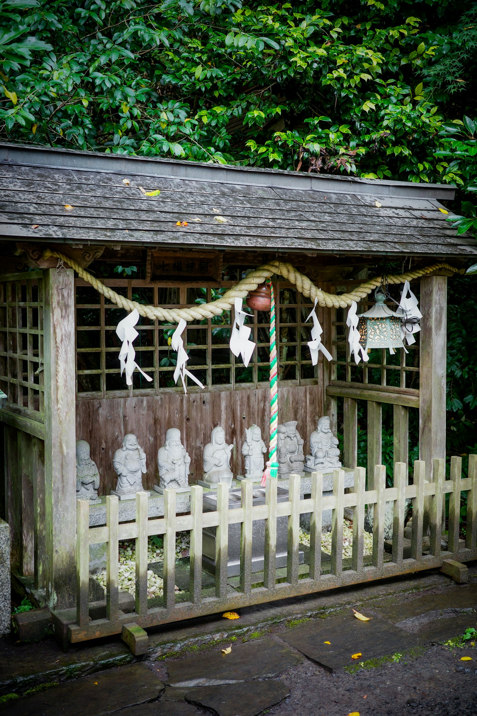 Une petite structure de sanctuaire avec des statues en pierre alignées dans un fond vert