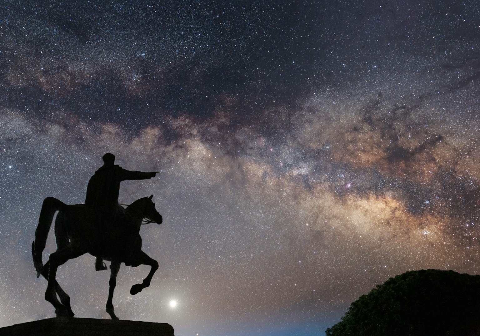 星空下的骑马雕像轮廓与银河