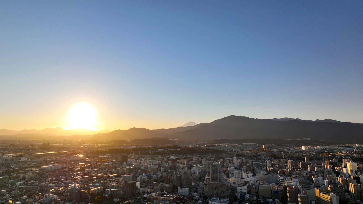 Vista panoramica di una città al tramonto con montagne sullo sfondo