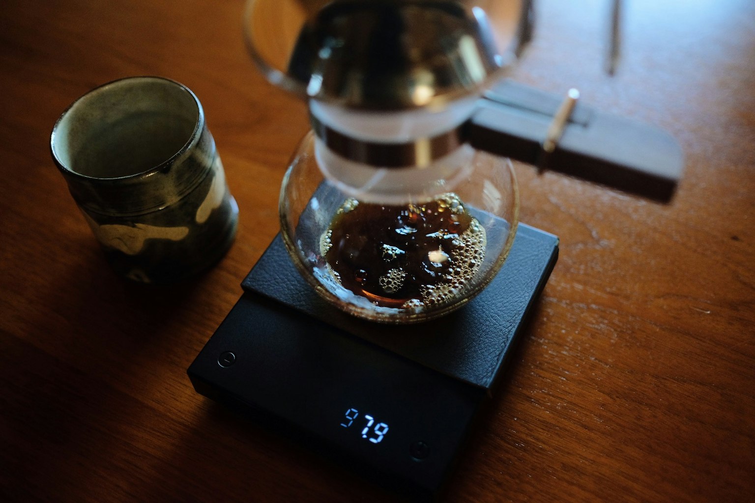Mesin kopi sifon sedang menyeduh kopi di atas timbangan digital dengan biji kopi