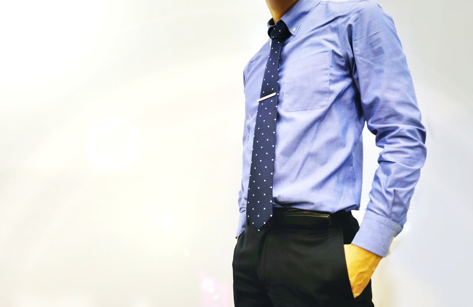 Man in blue shirt and tie with hands in pockets