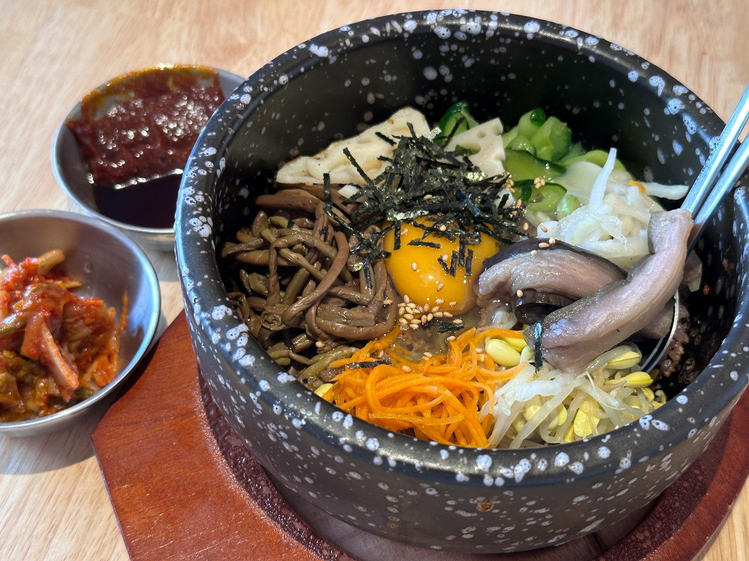Bibimbap servi dans un bol en pierre avec des légumes et un œuf