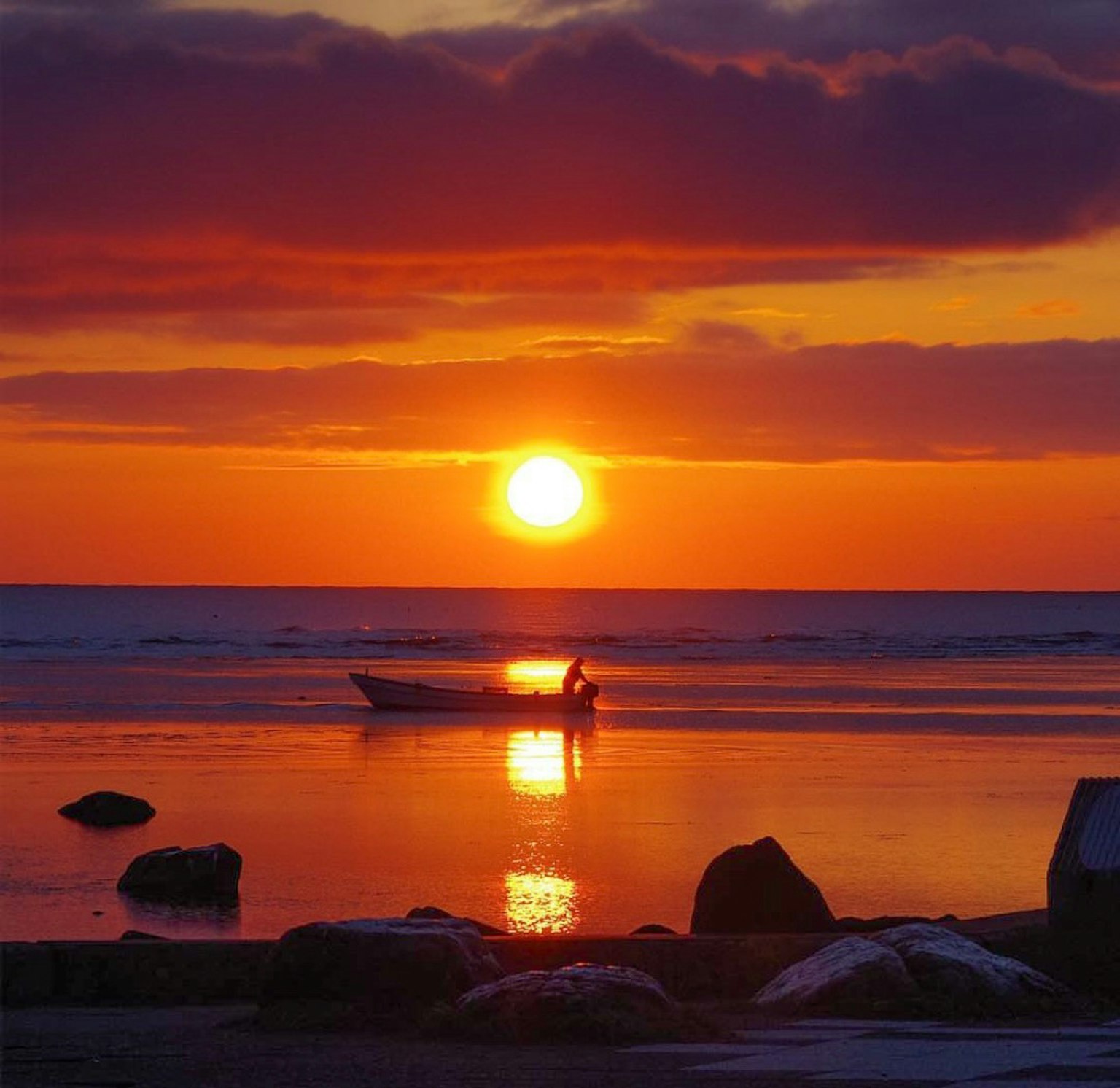Un bellissimo tramonto sul mare con una piccola barca che galleggia sull'acqua