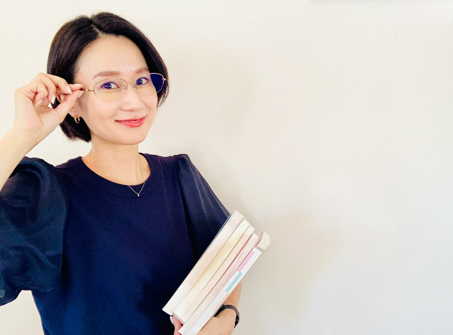 Người phụ nữ trong áo xanh đang mỉm cười khi cầm sách
