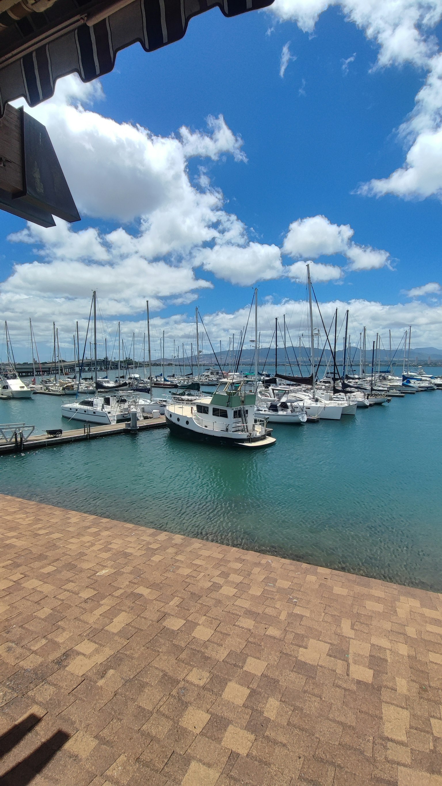 Vista del porto con yacht ormeggiati sotto un cielo azzurro e nuvole bianche