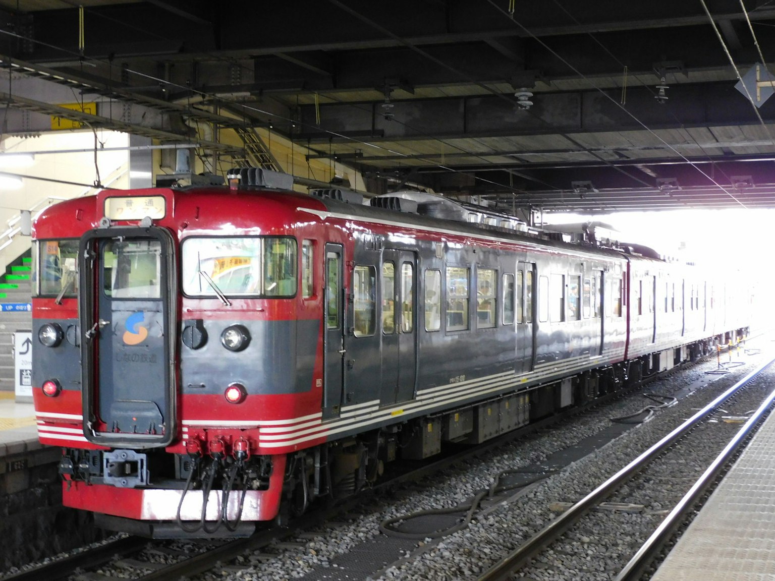 Kereta merah dan hitam berhenti di platform stasiun