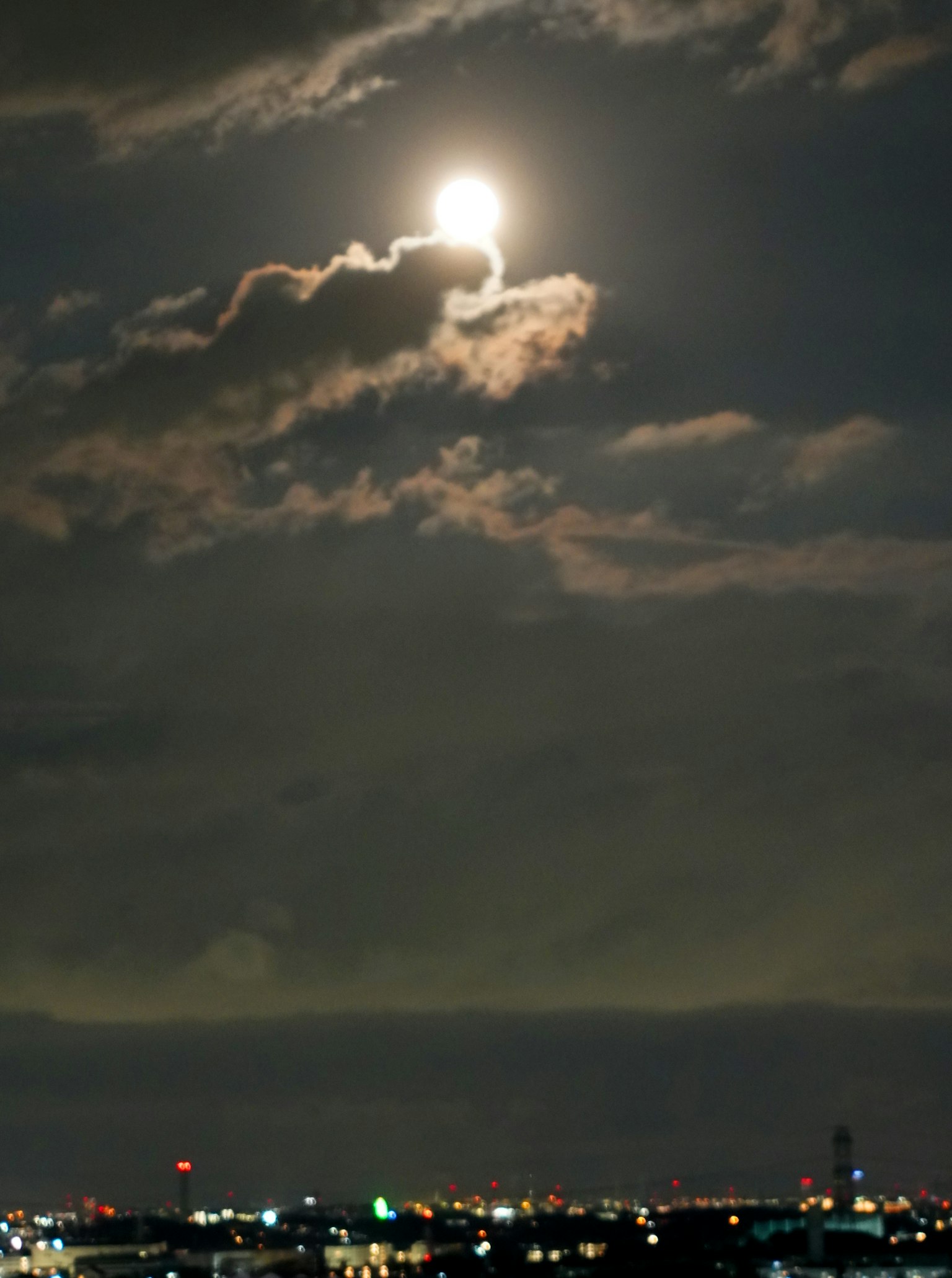 Lune brillante dans le ciel nocturne partiellement cachée par des nuages