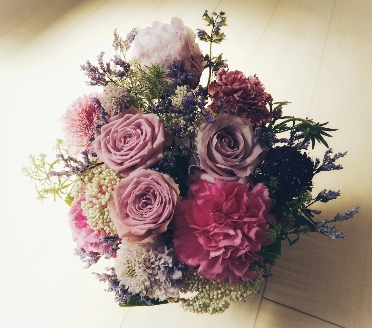 五彩缤纷的花束，包含粉色和紫色玫瑰及康乃馨，背景明亮