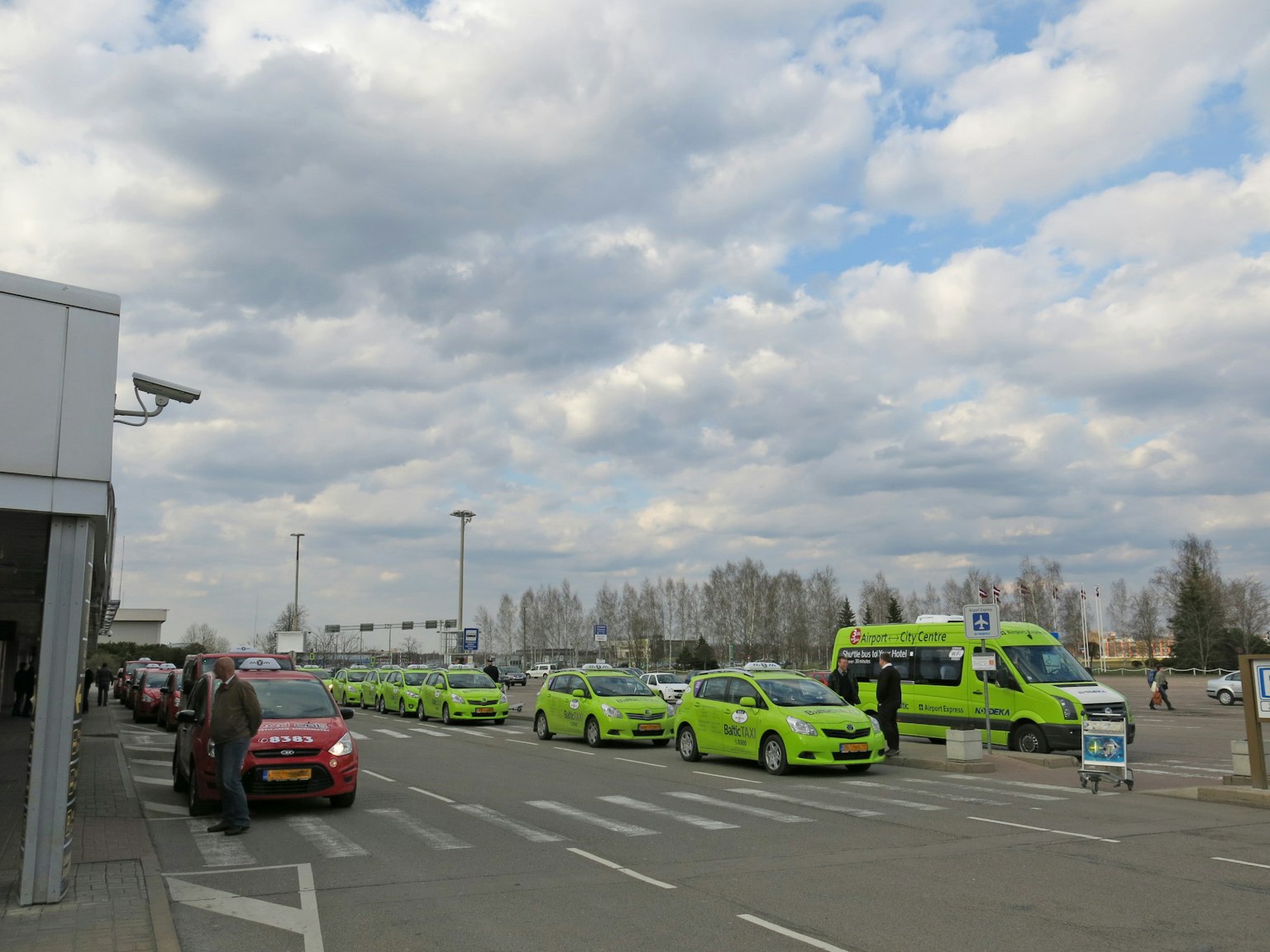 Taxis verts alignés à un stand de taxi d'aéroport sous un ciel nuageux