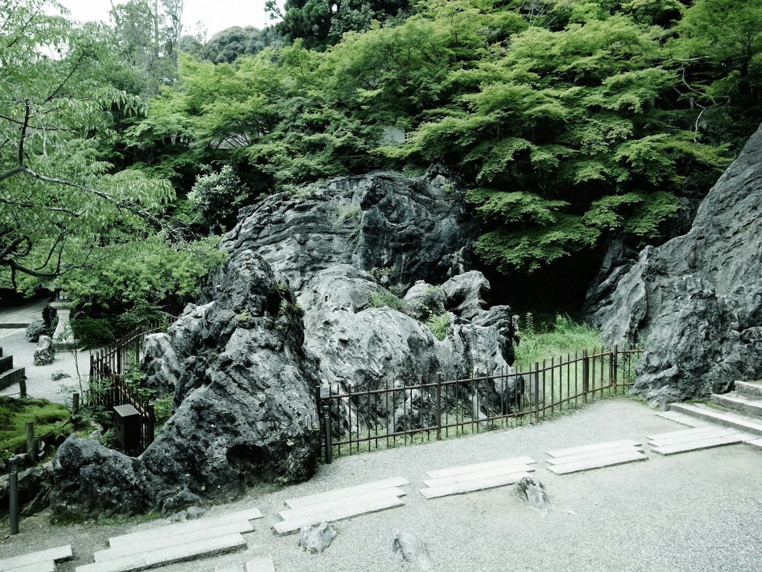 Paisaje de jardín exuberante con grandes rocas y escaleras de piedra