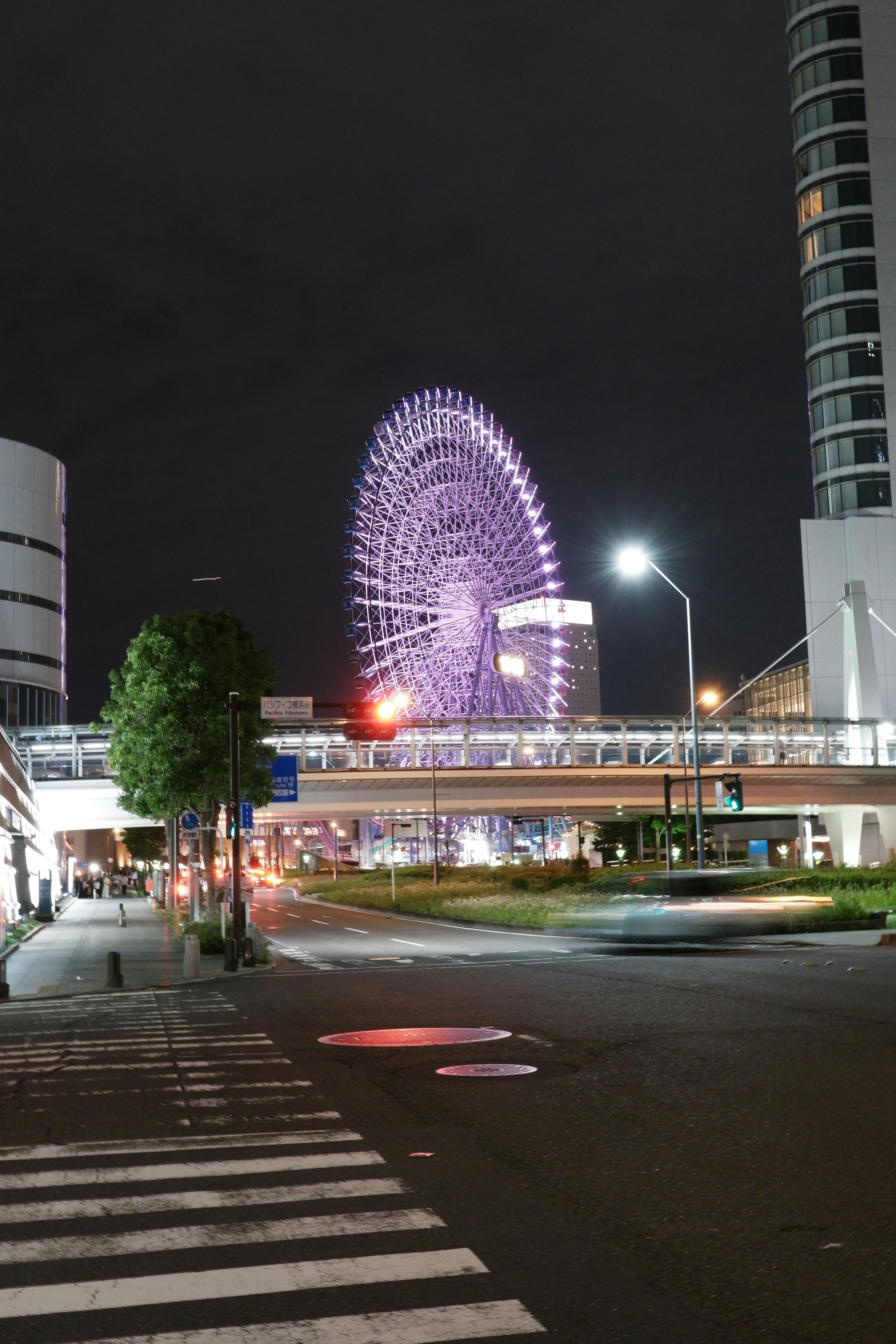 夜の都市で光る観覧車と高層ビルのある交差点