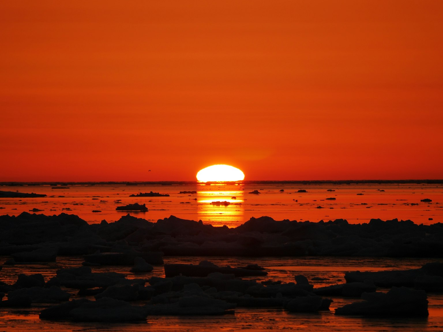 Sunset over icy waters with an orange sky