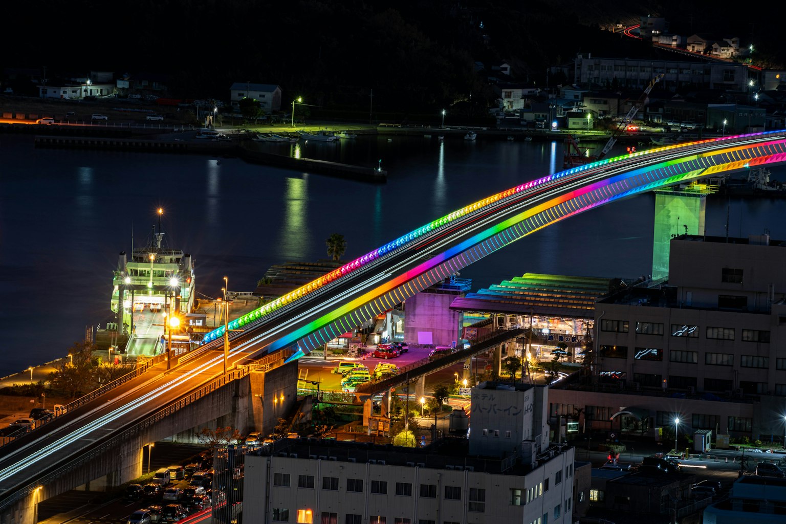 Ponte arcobaleno vibrante illuminato di notte sopra un porto