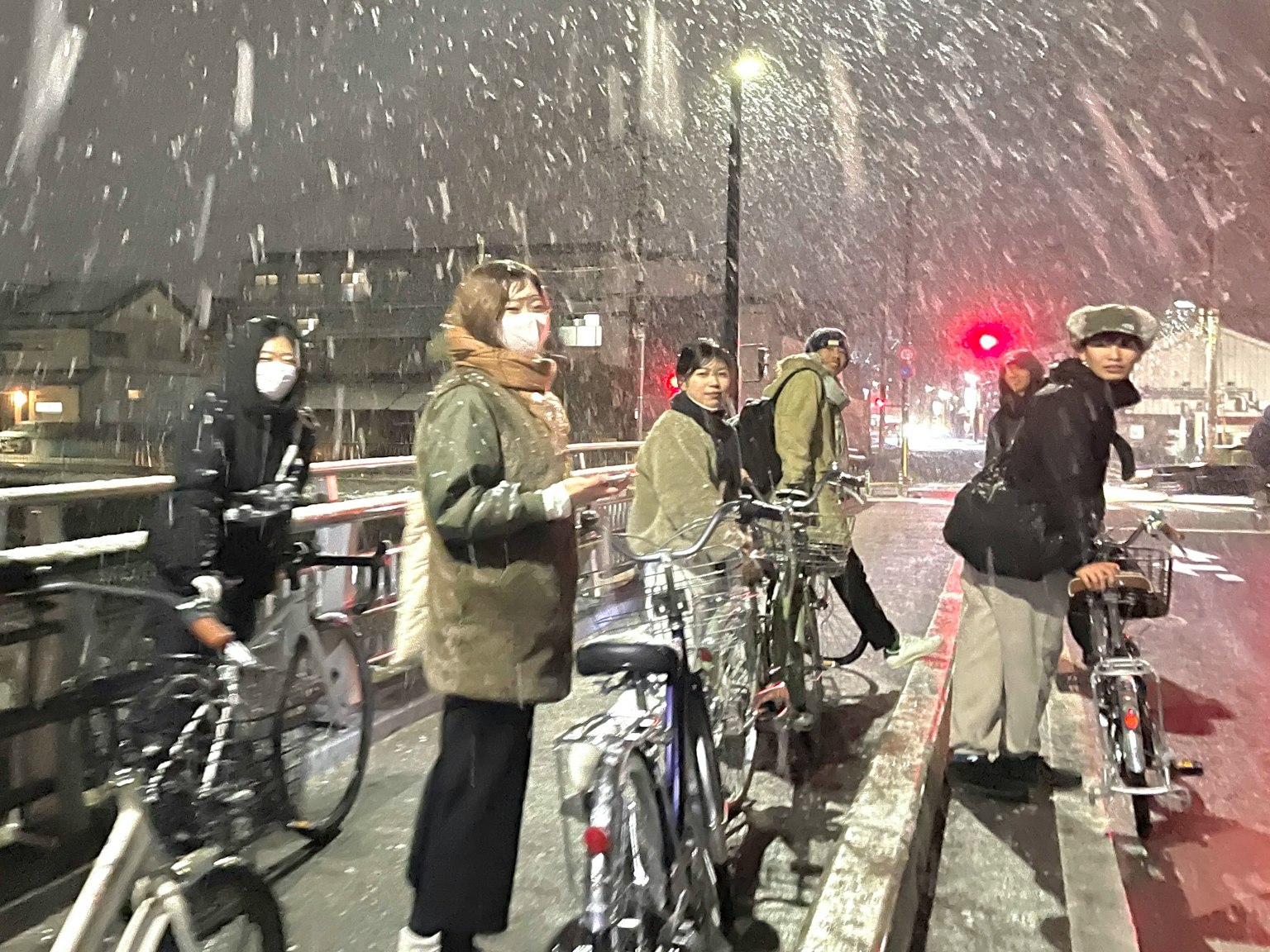 Eine Gruppe von Personen steht mit Fahrrädern im Schnee
