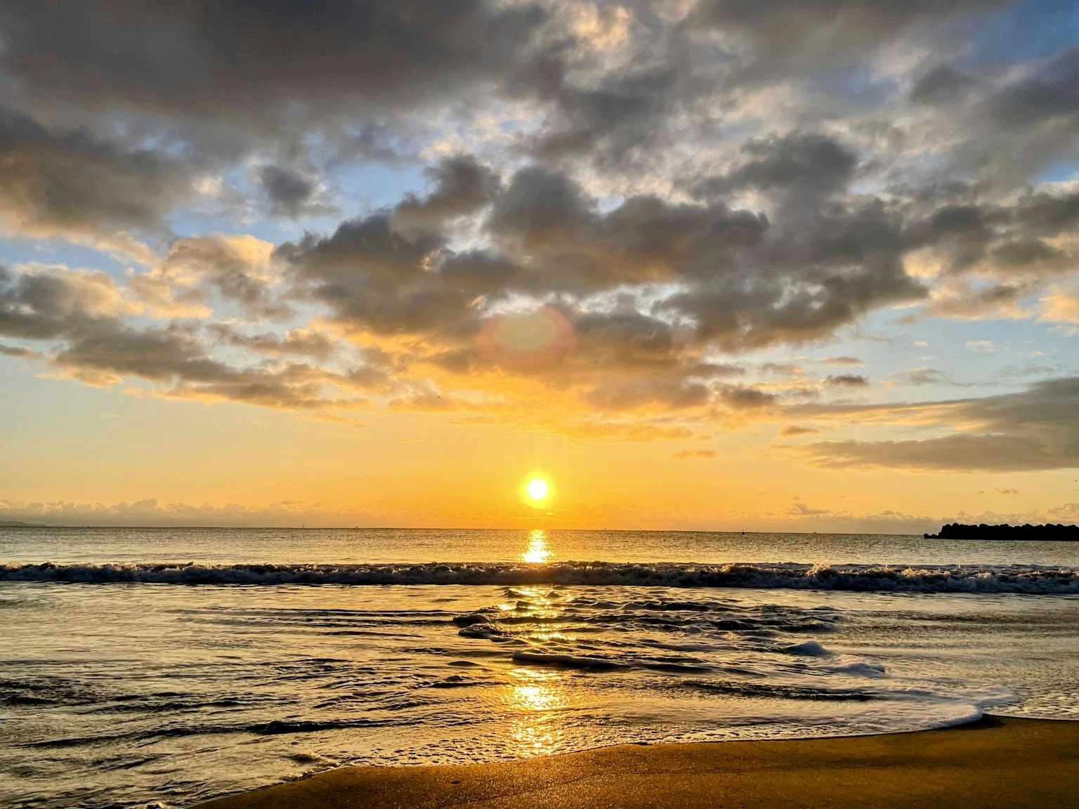 Una vista panoramica del tramonto sull'oceano con nuvole e onde calme