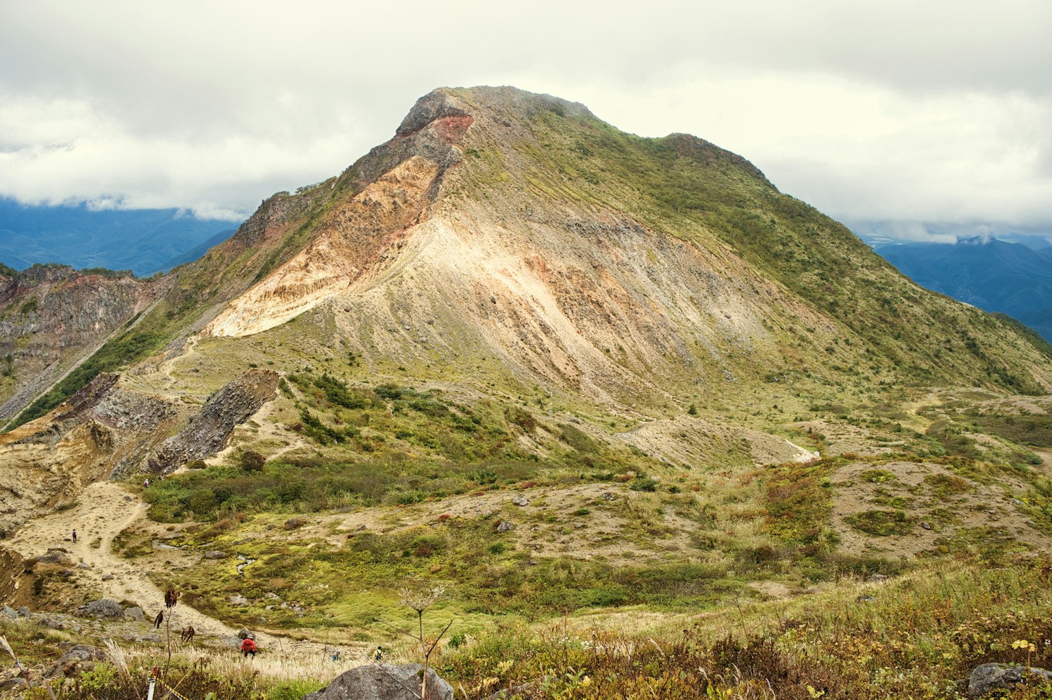 Berglandschaft mit grasigem Terrain und bewölktem Himmel