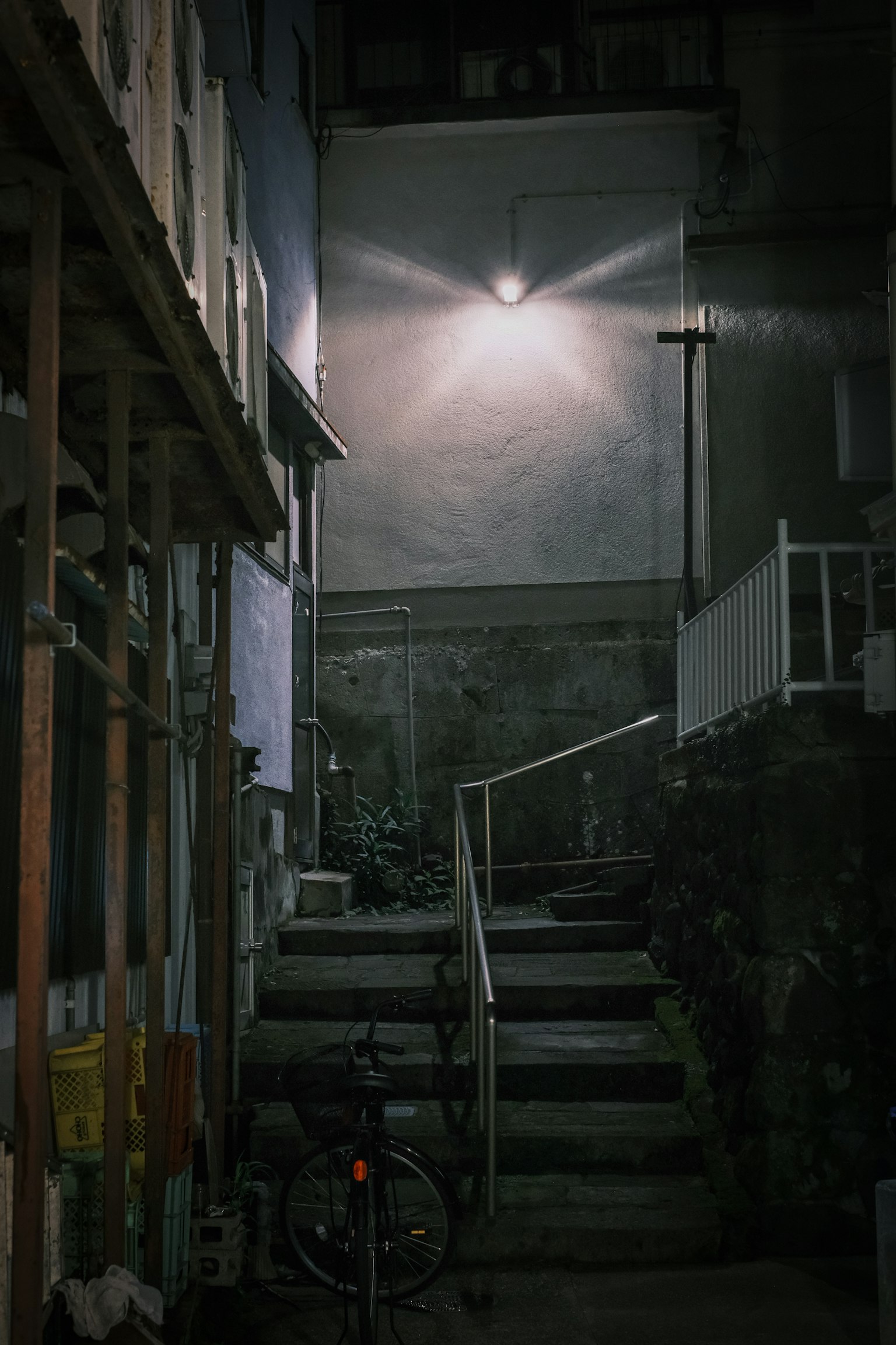薄暗い路地にある階段と自転車のある風景