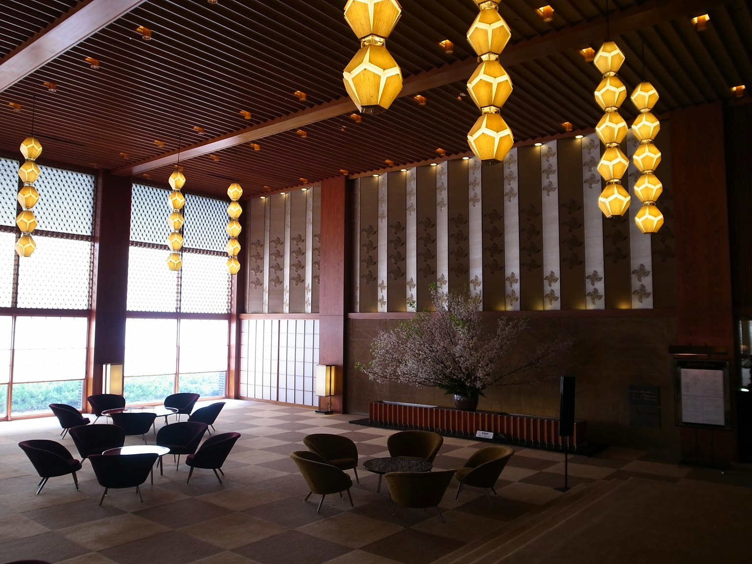 Modern lobby interior design with bright lighting and wooden ceiling featuring large windows for natural light