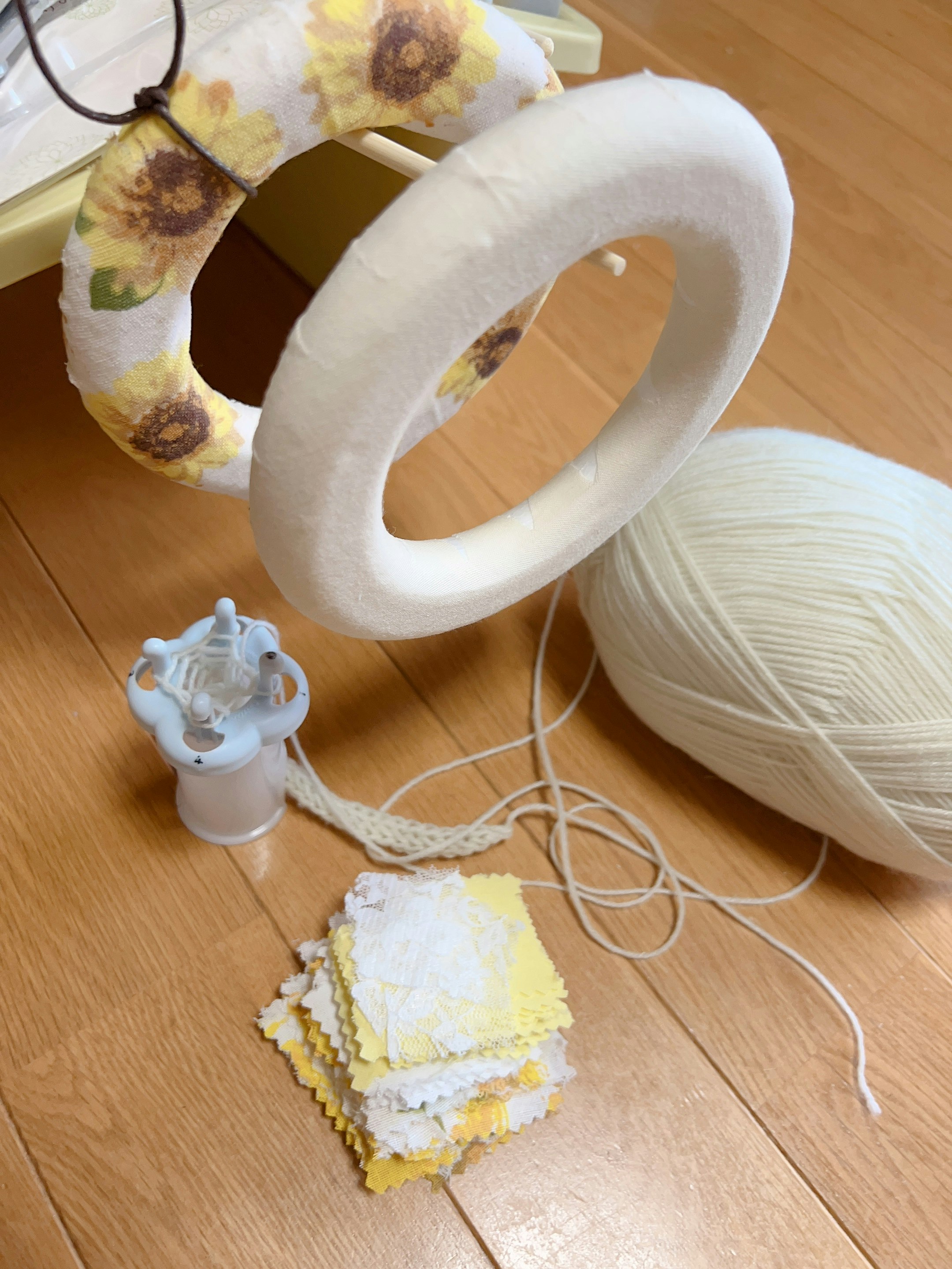 yarn balls and a partially knitted fabric on a wooden floor