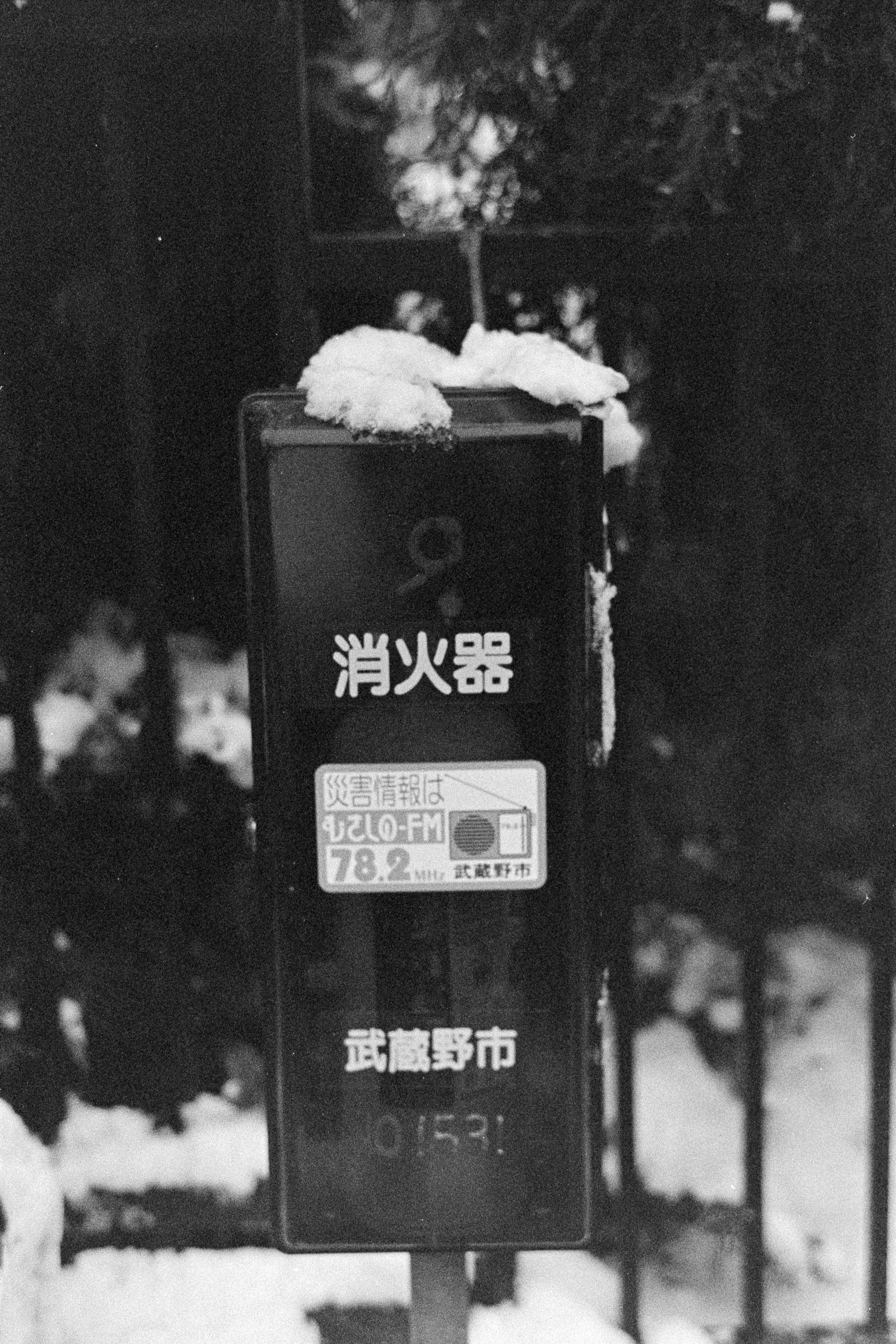 消火器と雪の降る街の標識が並ぶ夜の路上