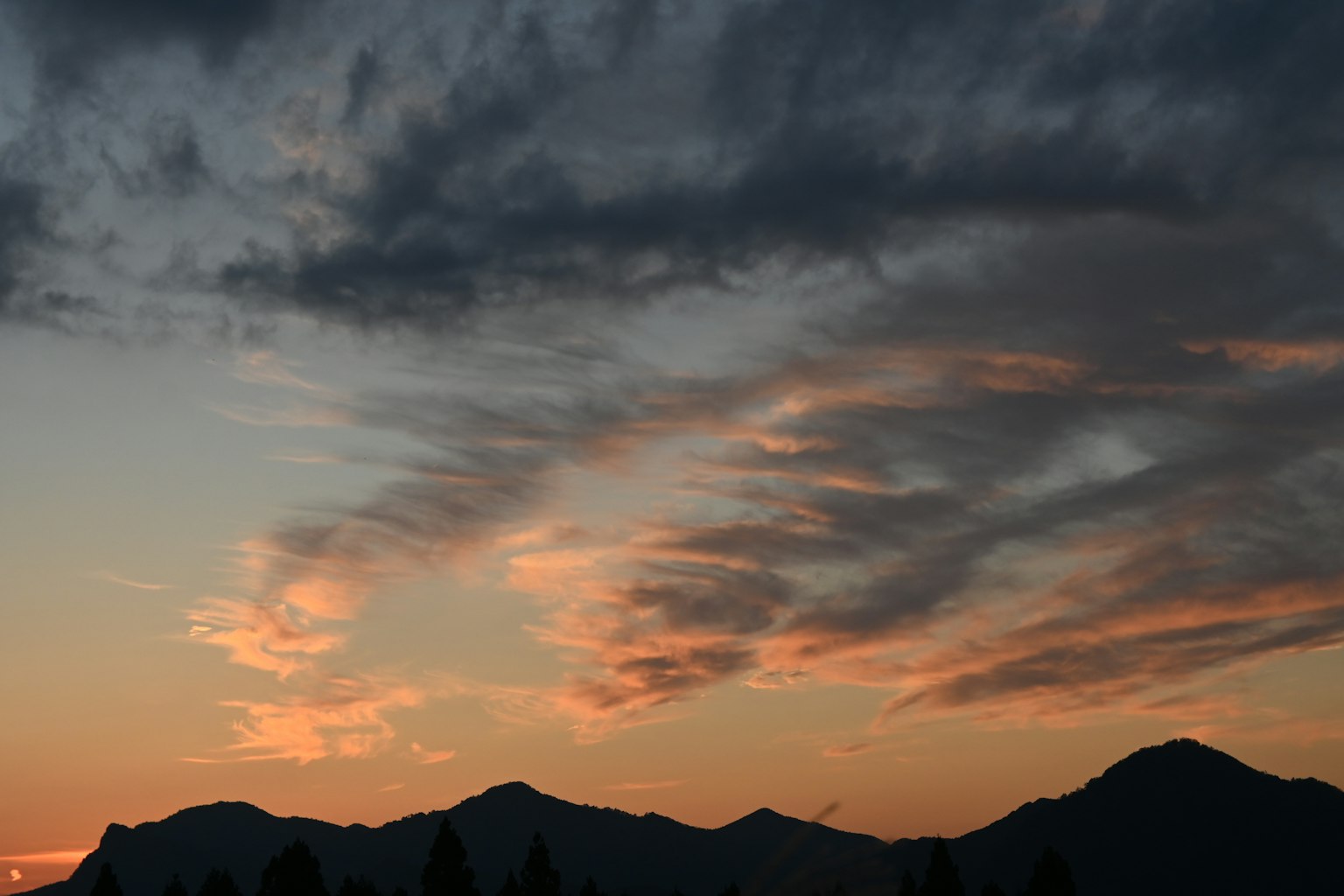 Silhouette di montagne contro un cielo al tramonto con nuvole colorate