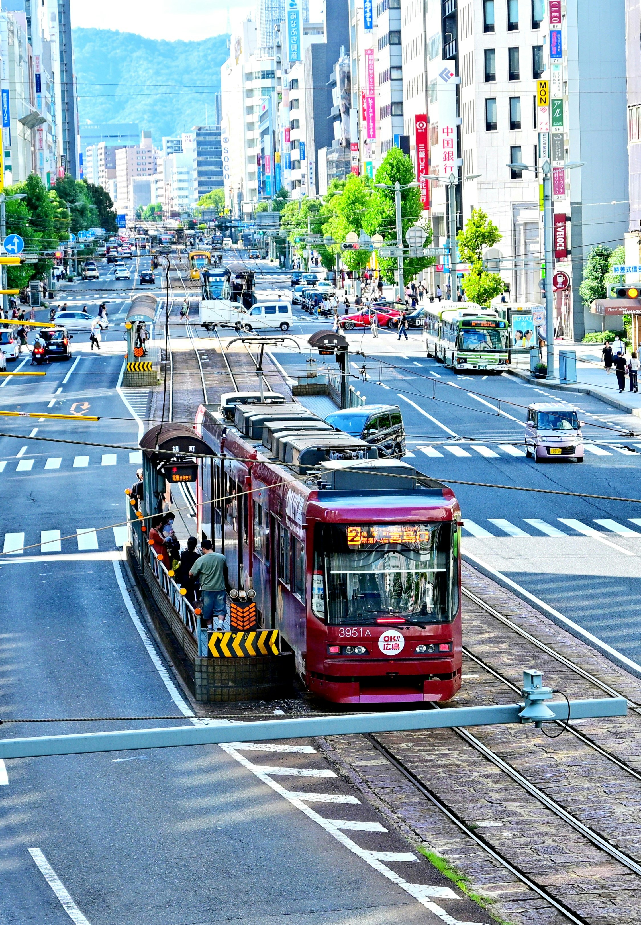 高層ビルの並ぶ大通りを走る路面電車のある風景