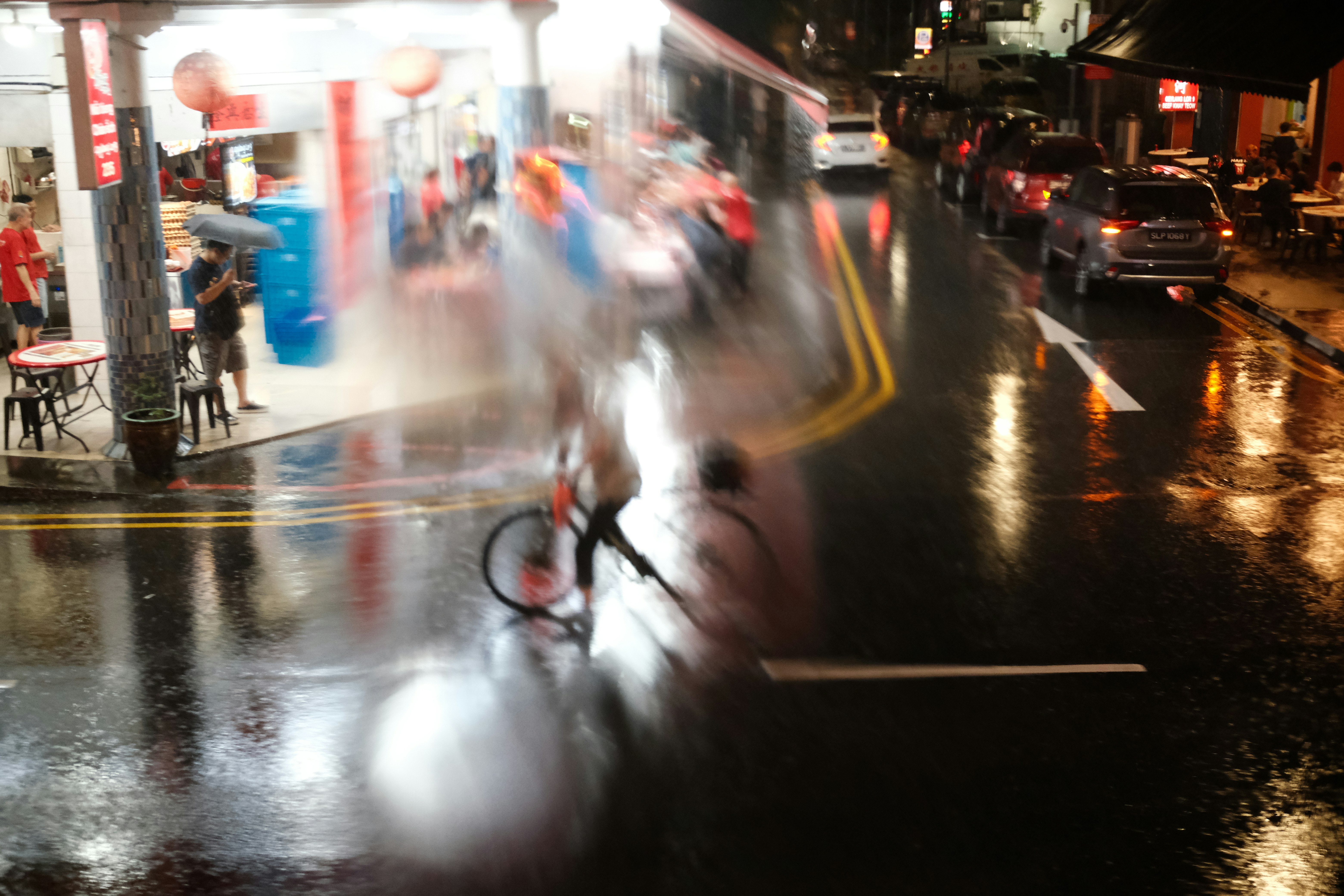 Bicicleta en una calle animada de noche con lluvia y peatones desenfocados