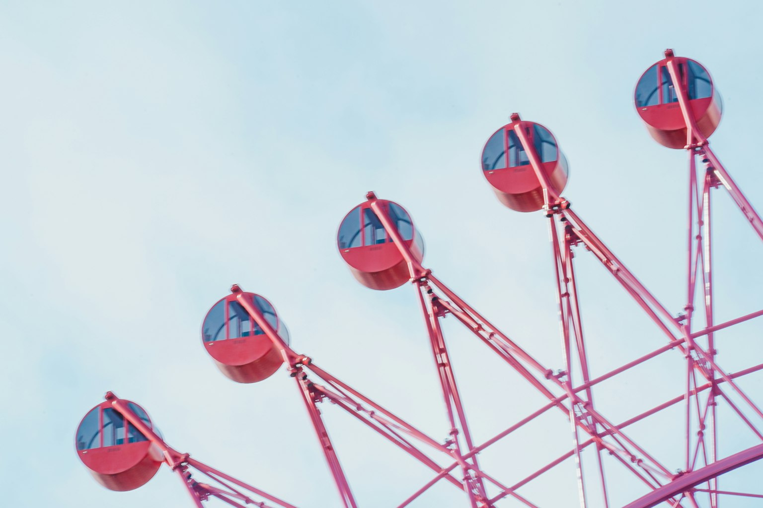 Kapsul roda ferris merah muda berjejer di bawah langit biru