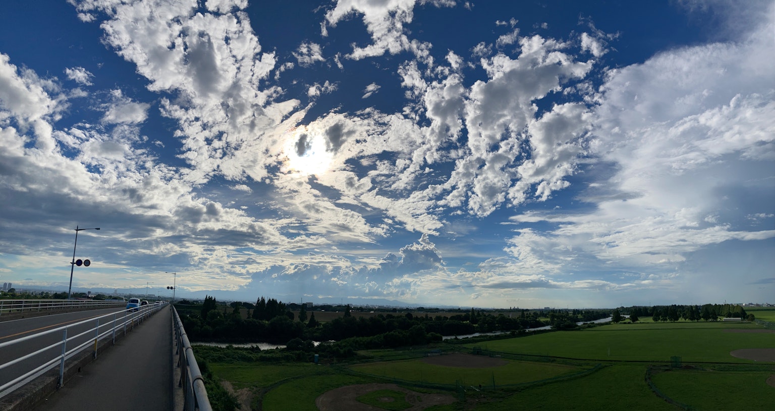 Vue panoramique d'un ciel bleu avec des nuages blancs dramatiques sur des champs verts