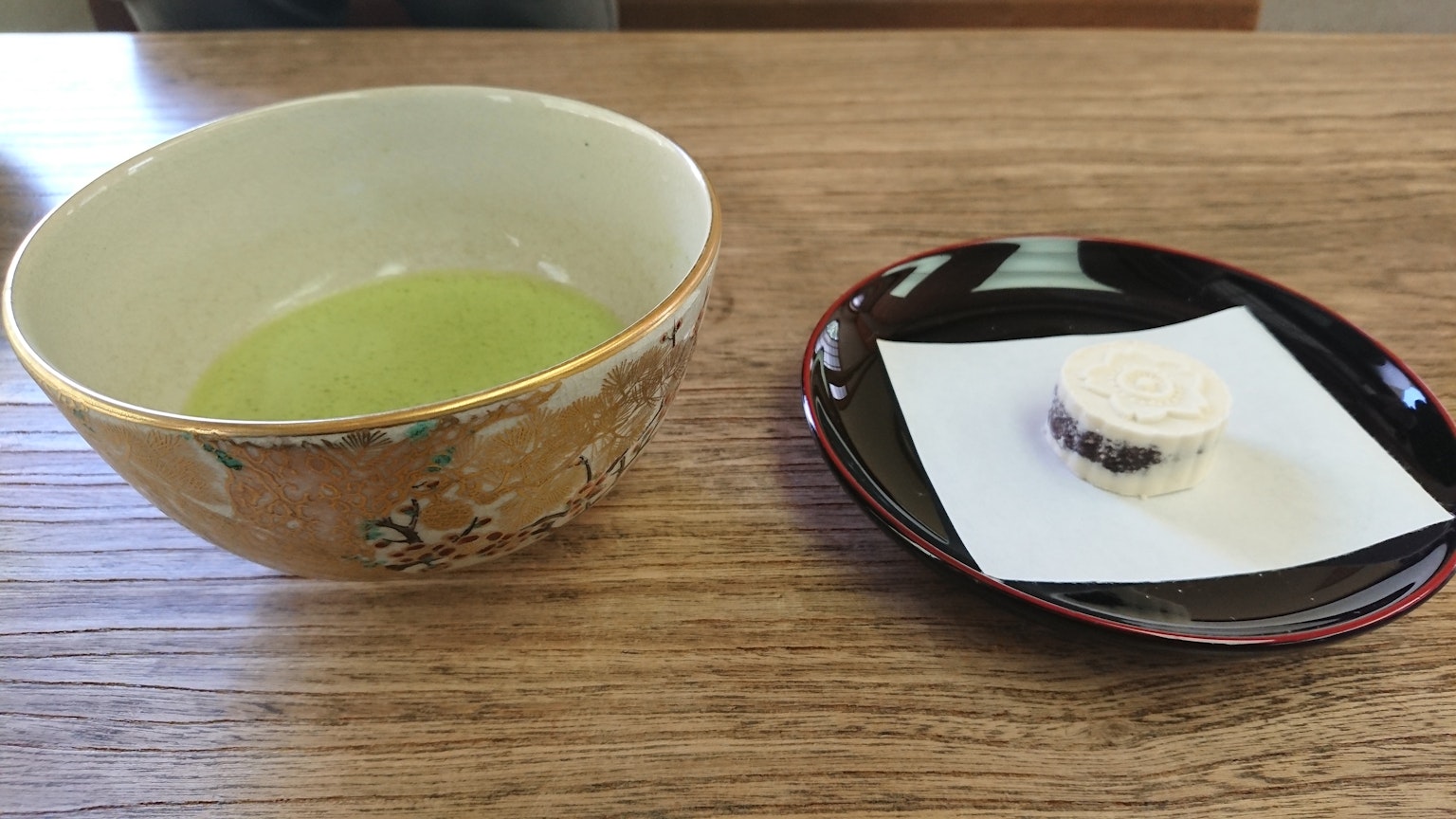 一碗绿茶旁边放着一盘传统日本甜点