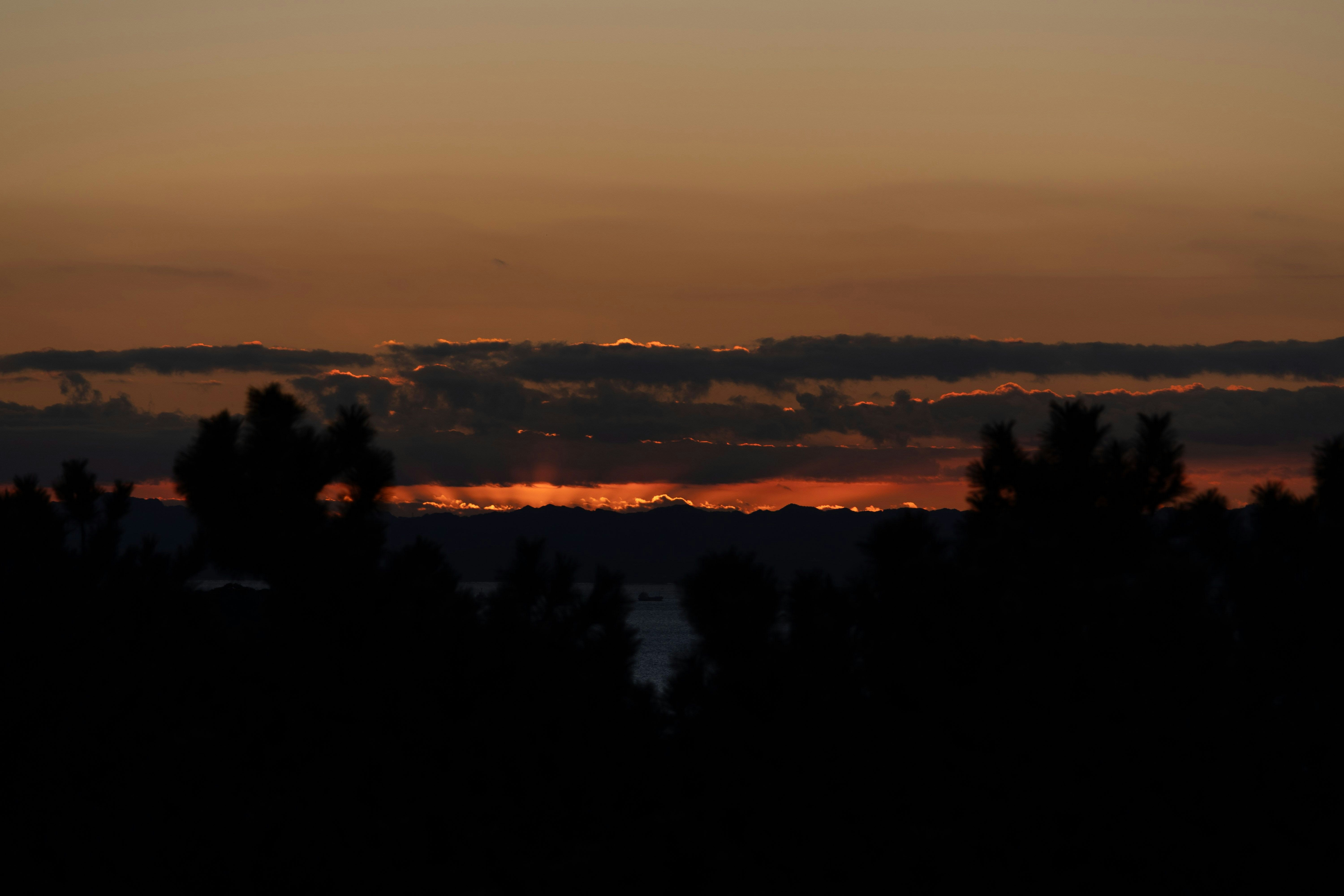 夕焼けの地平線と雲の帯が広がる風景