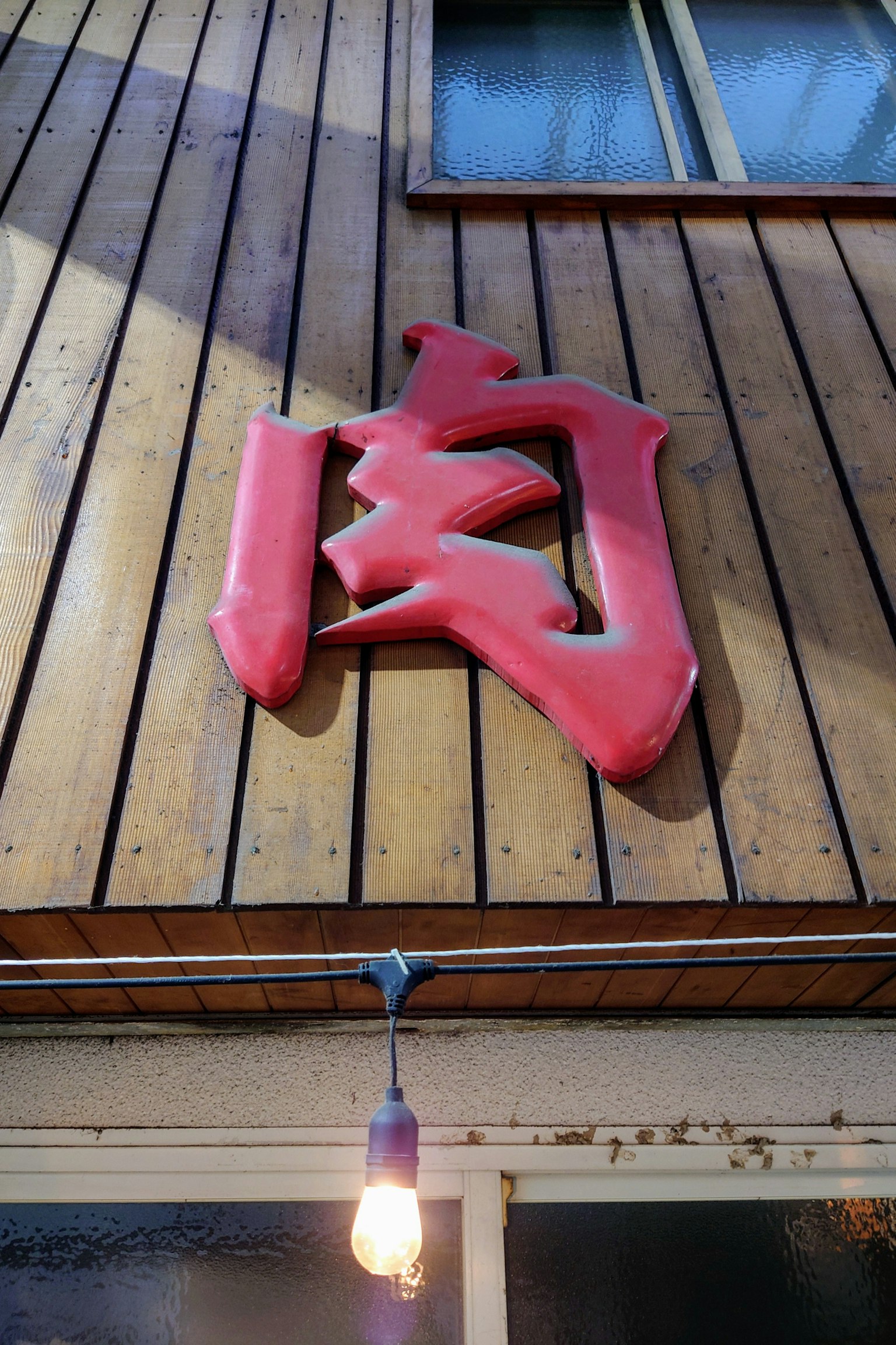 Rotes Kanji-Schild an einer Holzwand angebracht